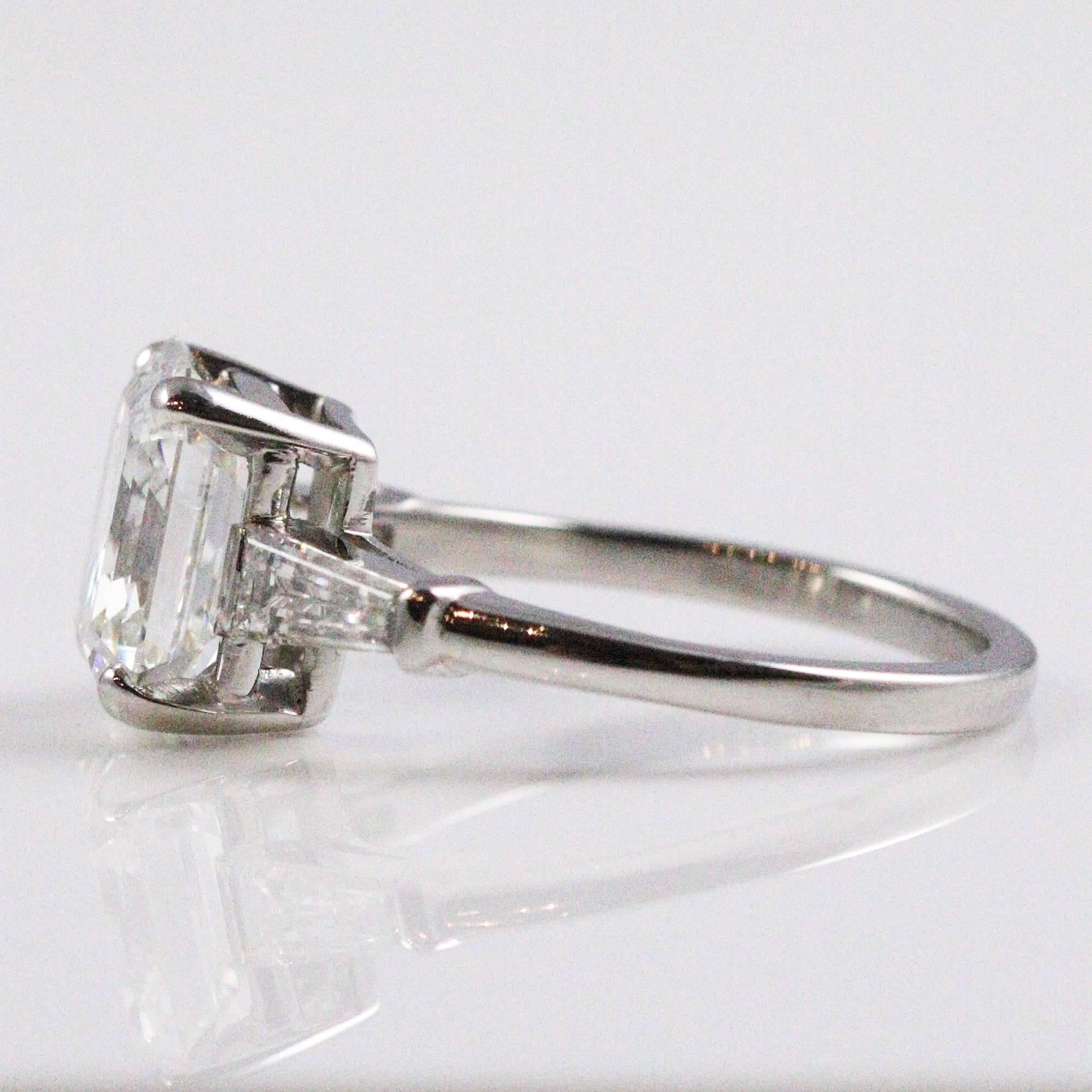 This breath taking ring features a squarish emerald cut diamond that slightly resembles an Asscher cut in appears. The stone measures 9.72 x 8.80 x 5.67mm, weighs 3.87ct and grades as 