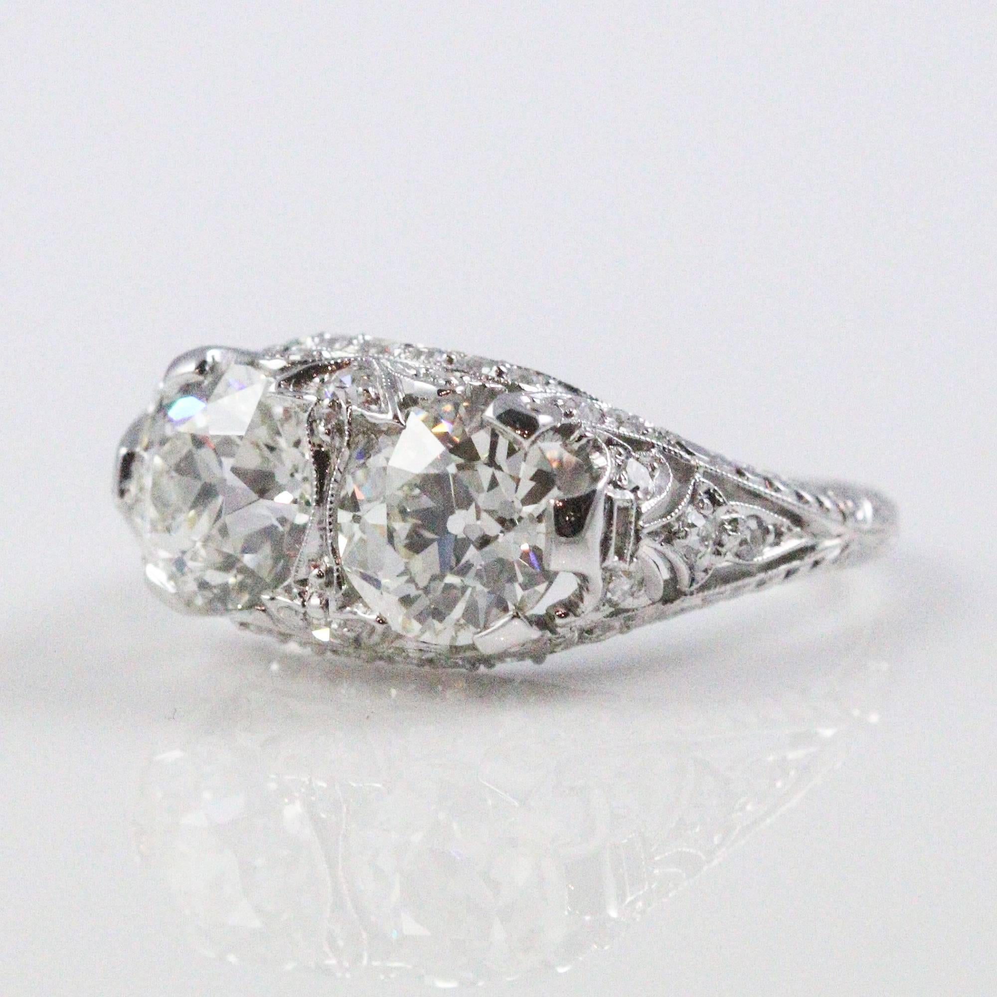 This stunning ring centers 2 old European cut diamonds, one of which weighs 1.28ct and grades as a 