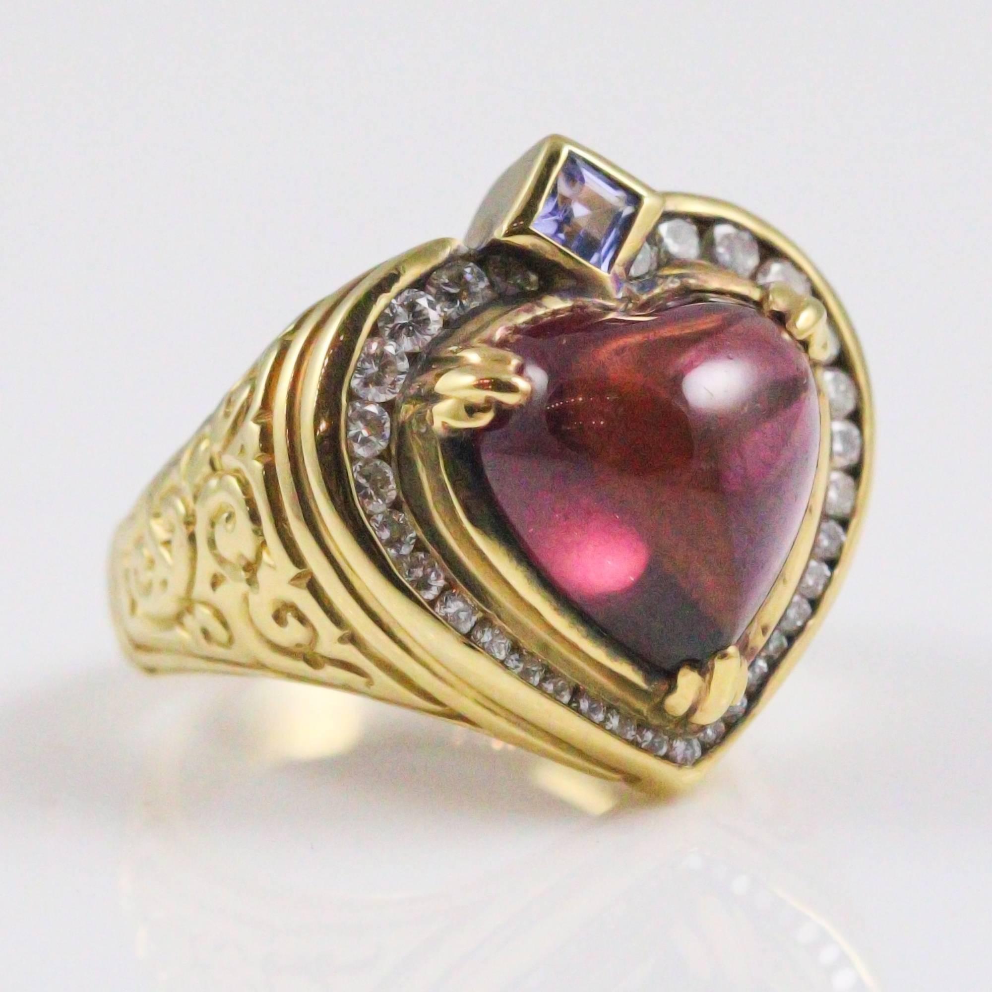 This beautiful ring by the designer, Seidengang, is constructed in 18k yellow gold focusing on a cabochon cut heart shaped rubellite tourmaline. The center stone is surrounded by a halo of 31 round brilliant cut diamonds (0.60ctw, F-G, VS) and a