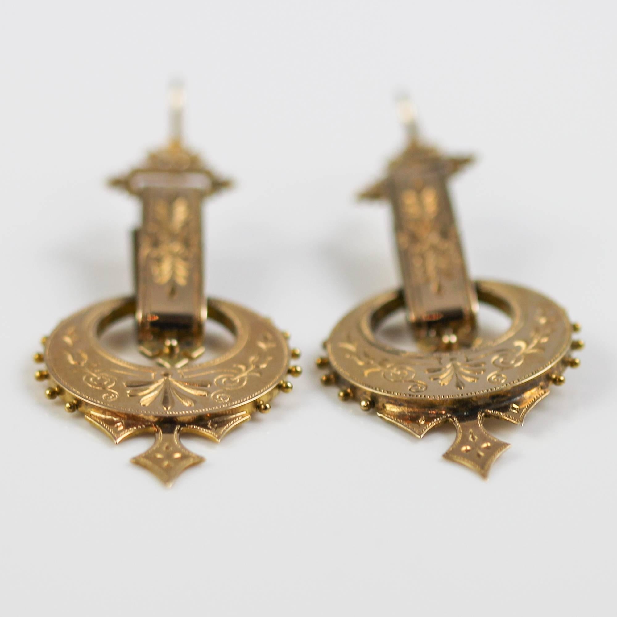 These beautiful Victorian earrings feature a beautiful design combining gothic styles with that of Art Nouveau. They are made in 14k yellow gold and decorated with intricate engraving and Etruscan style beading. They are in excellent shape