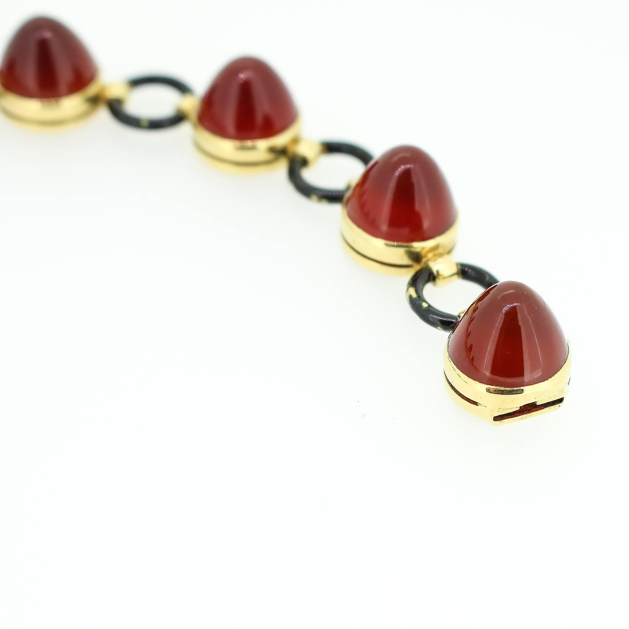 This unusual Art Deco bracelet features 8 cabochon carnelian set in 14K yellow gold and separated by yellow gold circle designs painted with black enamel. This creative design very accurately represents the culture and life of the 1920s.