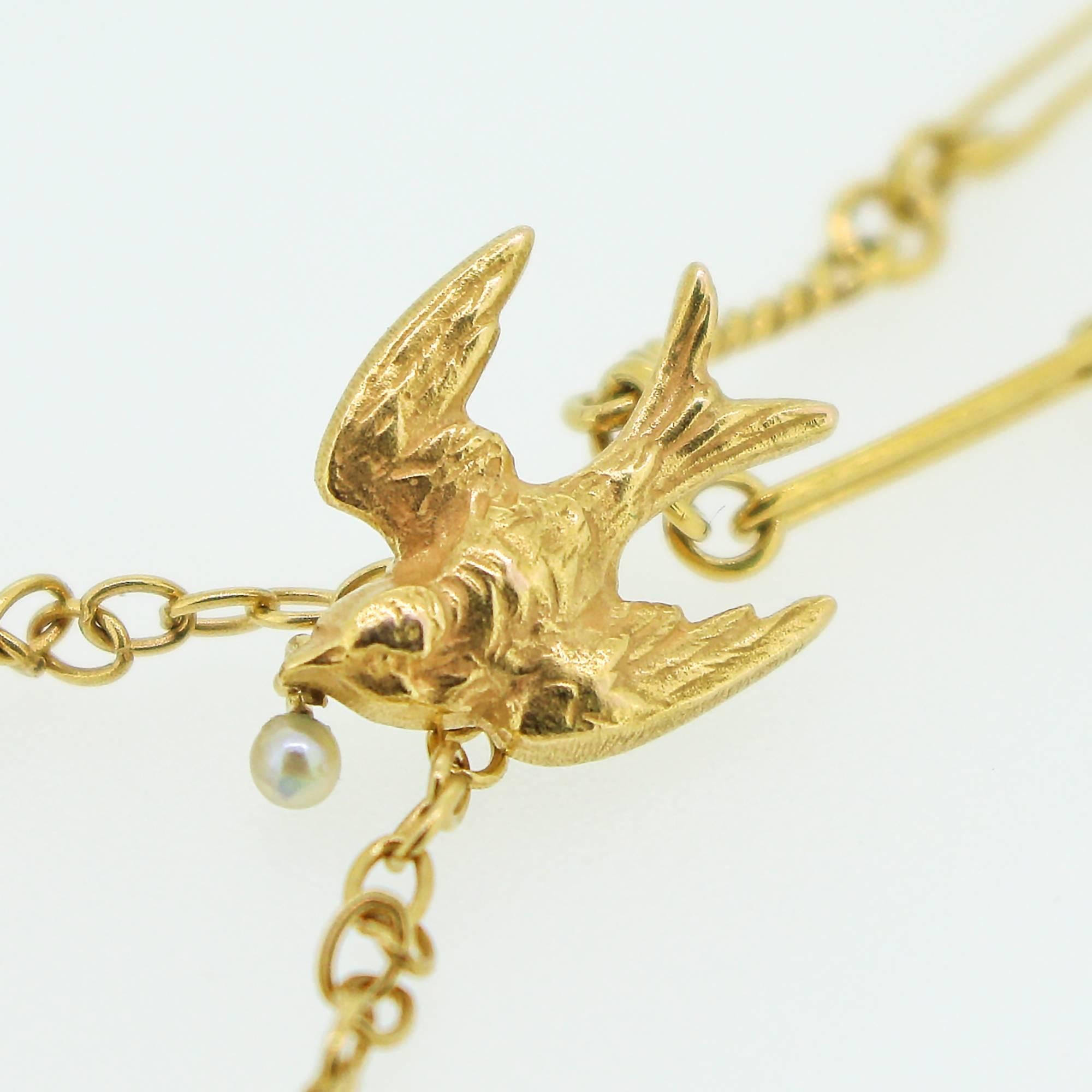 This 14k yellow gold necklace features 2 swallows at the base, joining together to hold a pear shape yellow diamond with a smaller swallow above holding a single, natural seed pearl. The birds are joined by a 14k yellow gold chain. The piece was