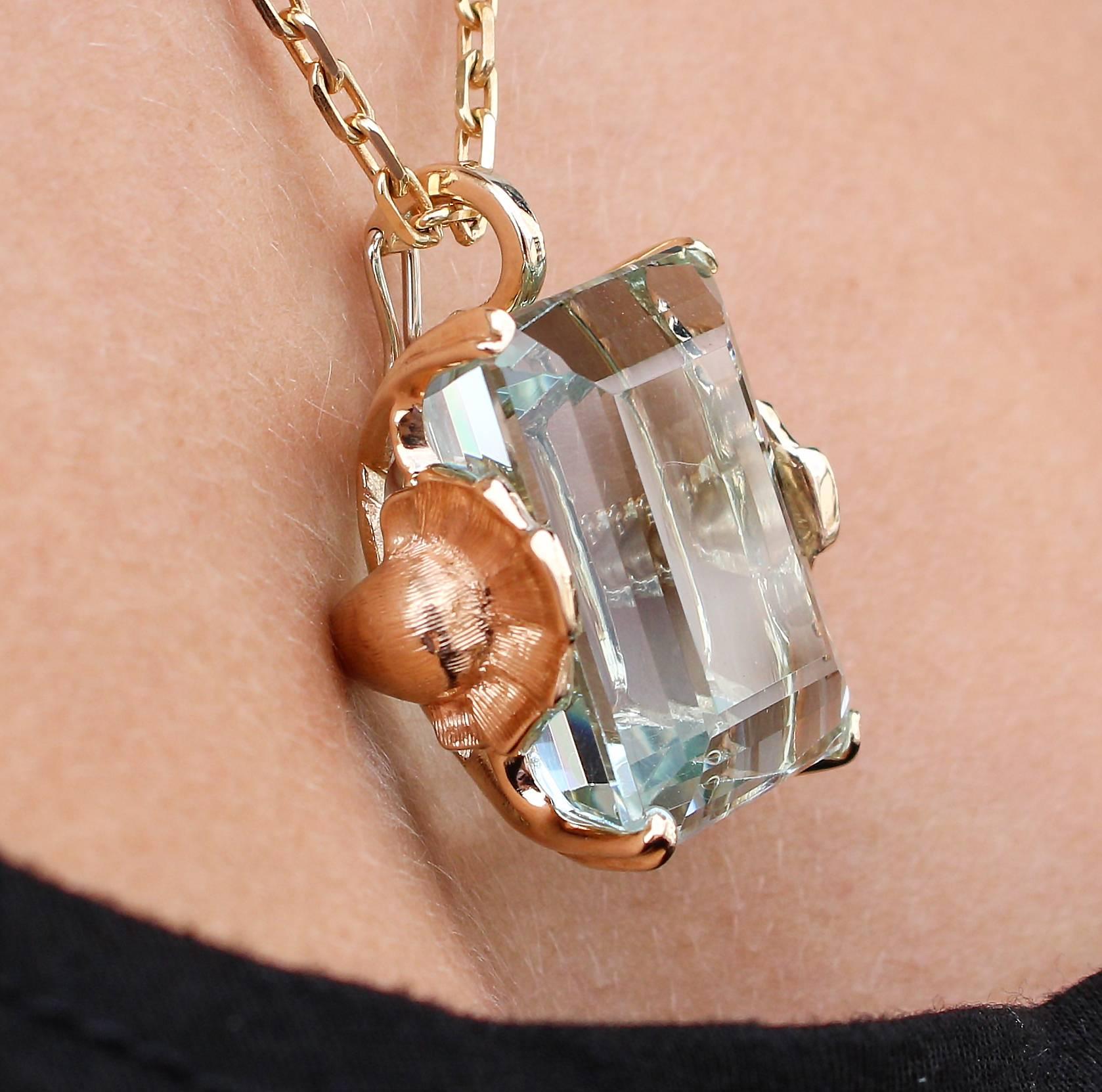 This 1940s Retro pendant features an emerald cut aquamarine, which measures 23 x 19mm and weighs approximately 47ct. The stone is set in a beautiful 14k yellow gold setting decorated by a flower on each side. The pendant's bail opens to allow the