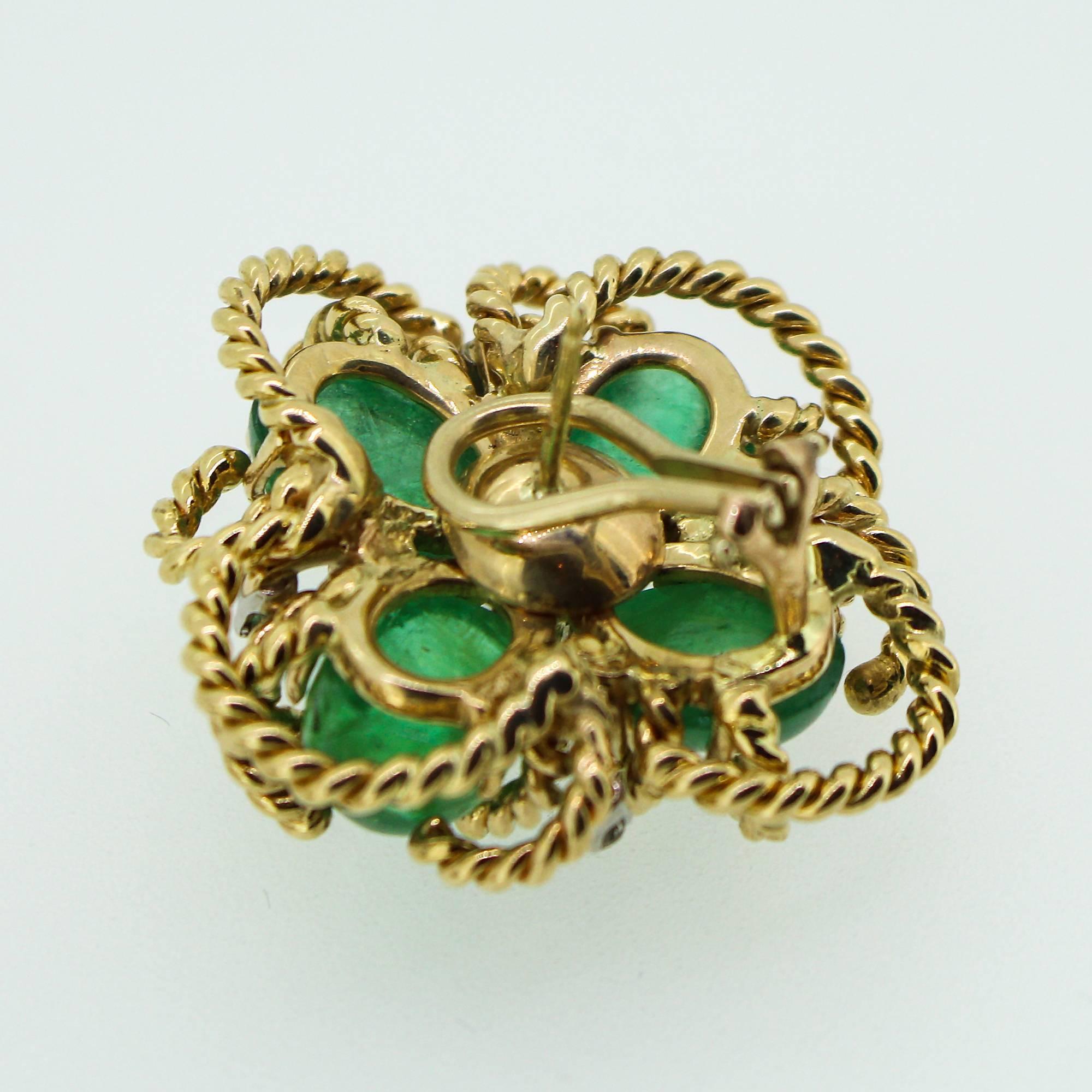 These beautiful 1970s Modernist earrings feature a 14k yellow gold textured cable cluster holding in place 4 cabochon cut emeralds in each earring, in what resembles a clover-style design. In the center of each earring sits an old mine cut diamond