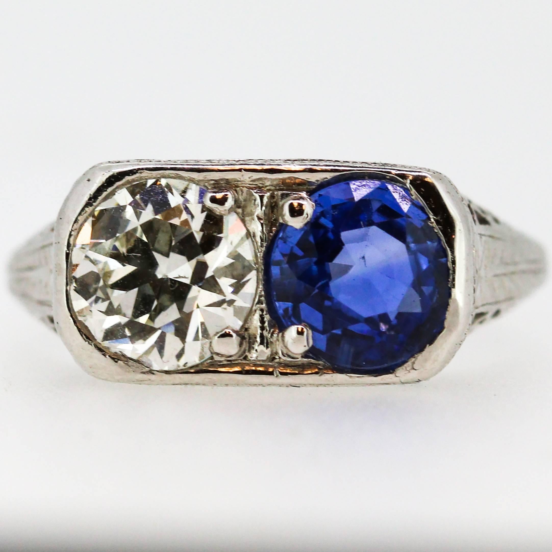This gorgeous Art Deco ring focuses attention around 2 main center stones: a 1.43ct round blue sapphire and 1.15ct old European cut diamond which grades as 