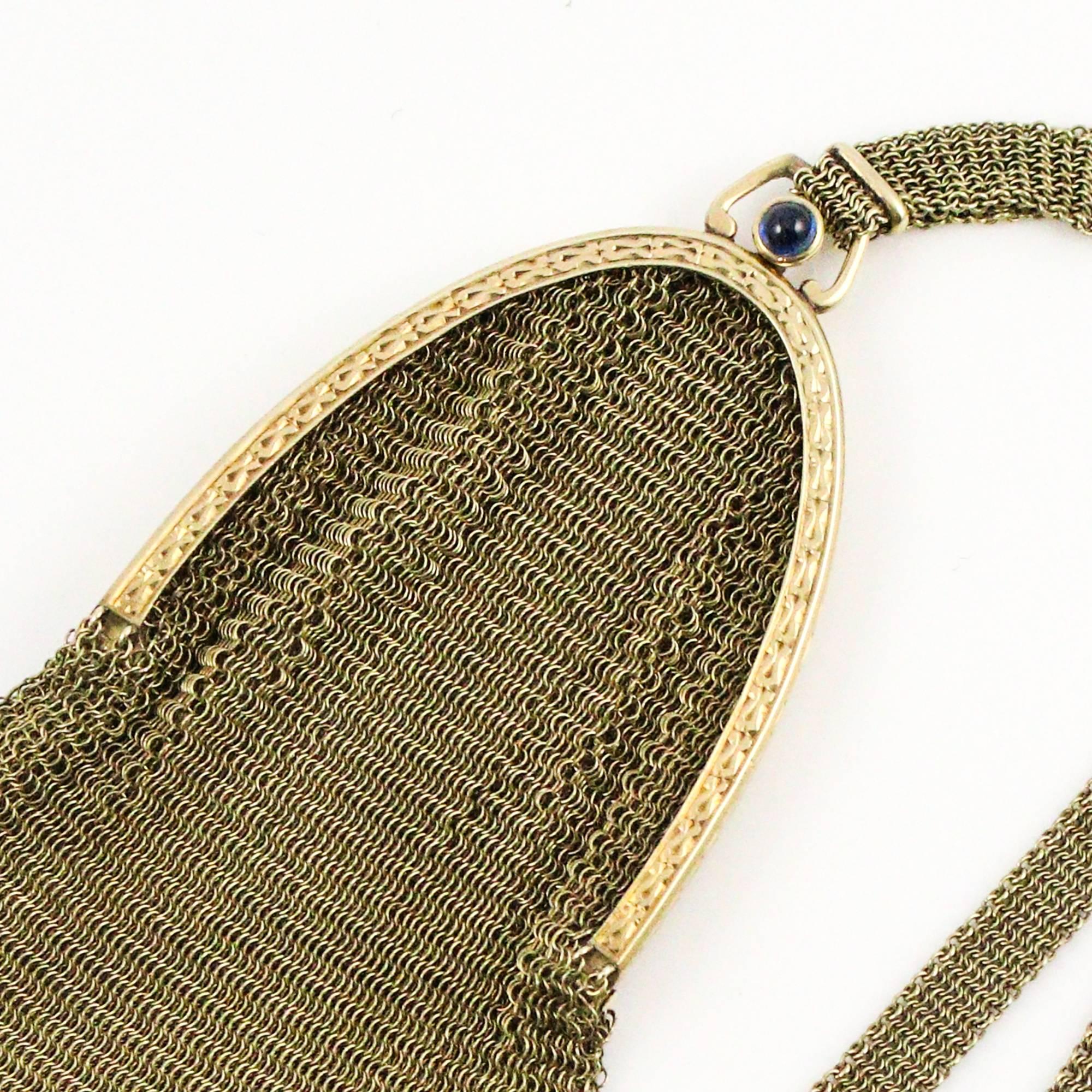 This Victorian mesh style 14k yellow gold purse features intricate designs of a seed pearl tassel drop, engraving on the rim, a wrist strap decorated with a floral sliding piece and a cabochon blue sapphire clasp. The purse is in remarkable shape