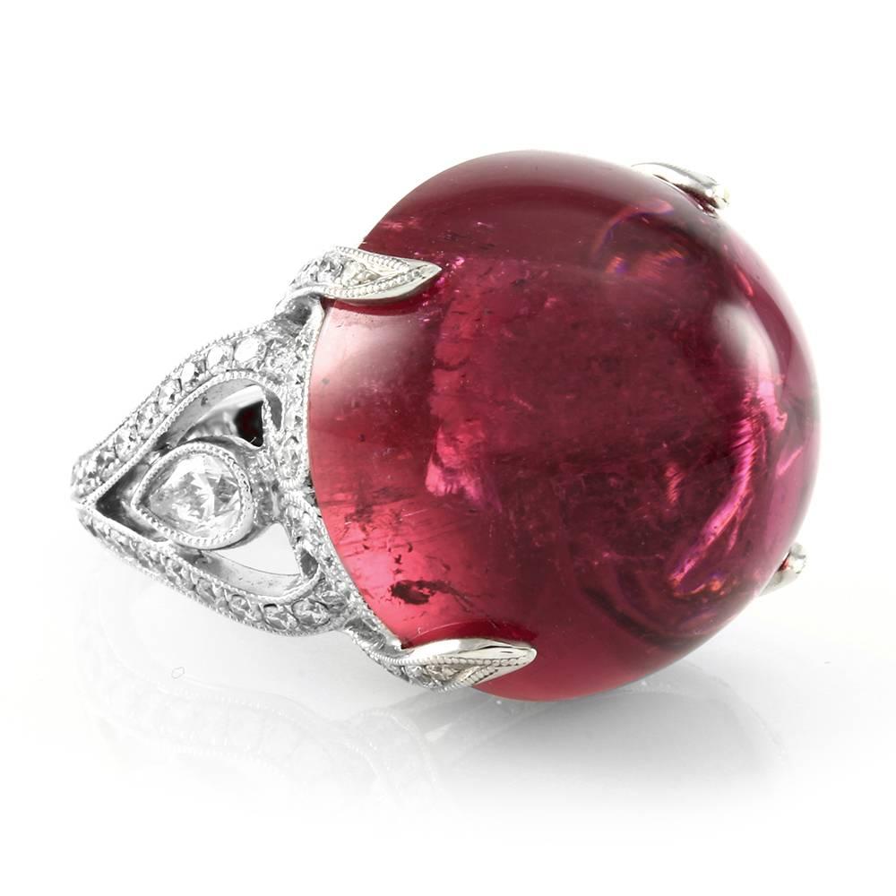 Custom pink tourmaline ring with pavé diamonds in high polished 18K white gold. There are one round cabochon cut tourmaline (37.31ct), two pear cut diamonds (0.50ctw) and one hundred fifty-four round brilliant cut diamonds (1.31ctw) with a color of