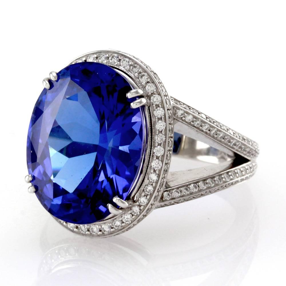 Oval tanzanite statement ring with pavé diamond halo and shoulders in high polished 18K white gold. There are one oval faceted cut tanzanite (11.56ct) and one hundred seventy-eight round brilliant cut diamonds (0.61ctw) with a color of F-G and a