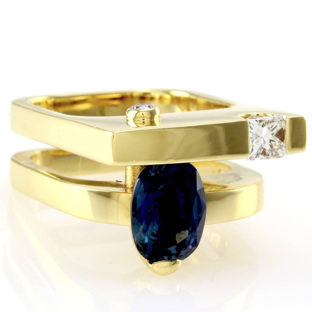 Sapphire statement ring with mixed cut diamonds in high polished 18K yellow gold. There are one oval faceted sapphire (2.85ct), one princess cut diamond (0.35ct), and one round brilliant cut diamond (0.09ct). The diamonds have a color of F-G and a