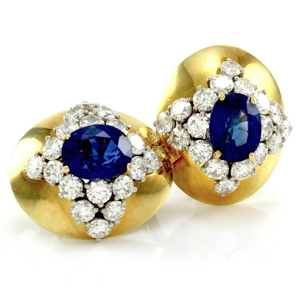 Genuine sapphire and diamond button earrings in high polished 18K yellow gold. There are two oval faceted cut sapphires and thirty-six round brilliant cut diamonds (5.52ctw) with a color of F-G and a clarity of VS1-VS2. The sapphires are prong set