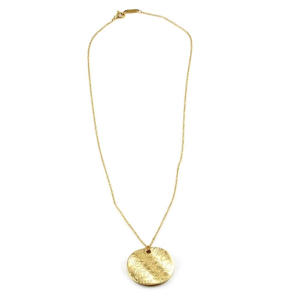 Signed designer Tiffany & Co. Notes round pendant necklace set in 18K yellow gold. The round concave pendant (24.1mm x 23.8mm) comes on a 1.1mm, Tiffany & Co. rolo chain that is 16 inches long with a spring ring clasp. This necklace has a total
