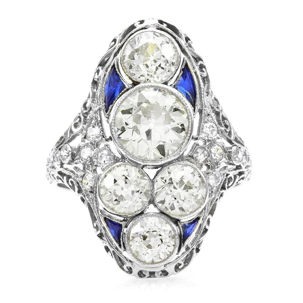 Antique Edwardian five stone diamond shield ring with sapphire accents in high polished platinum. In the center there are one bezel set, European cut diamond (1.12ct) with a color of K and clarity of SI1 and four additional bezel set, European cut