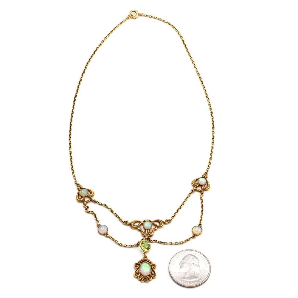 Art Nouveau opal and peridot lavalier necklace set in satin finish 14K yellow gold. There are five round and one oval cabochon cut opals total (1.67ctw) and one round faceted peridot (0.95ct). The peridot is bezel set and the opals are bezel set