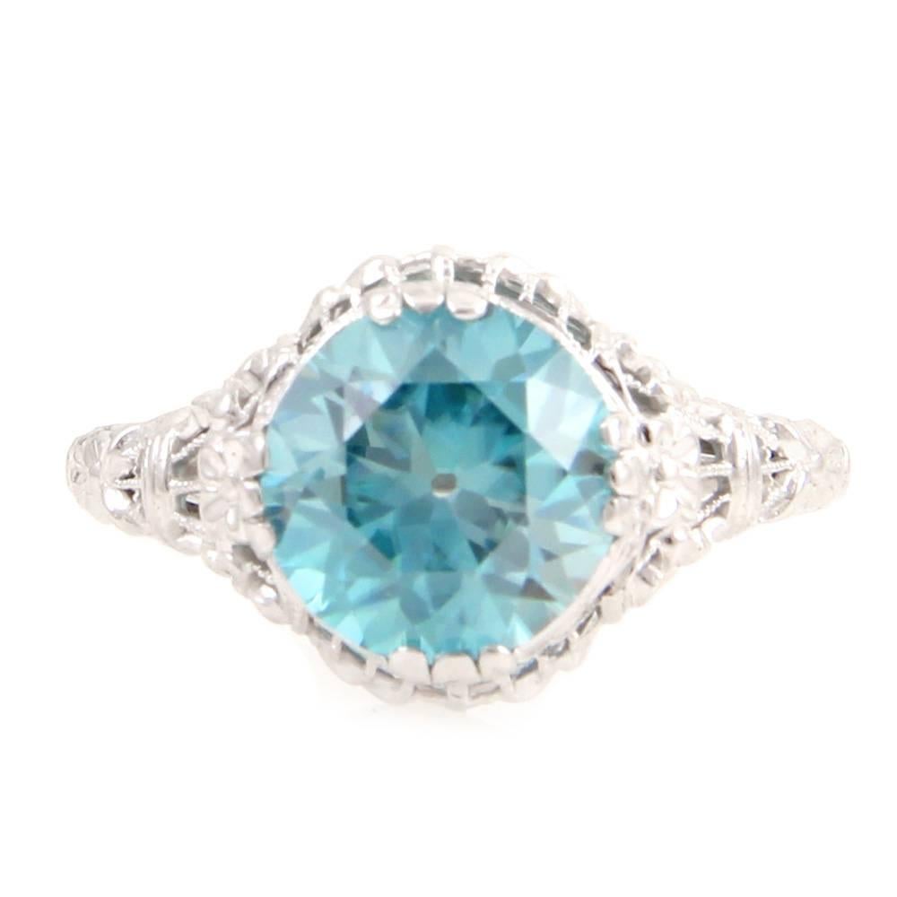 Vintage upcycled round faceted blue zircon solitaire filigree ring set in 18K white gold. There is a round faceted zircon (4.37ct) with cut culet. The ring is set in high polished 18K white gold with filigree detail. The overall size of this ring is