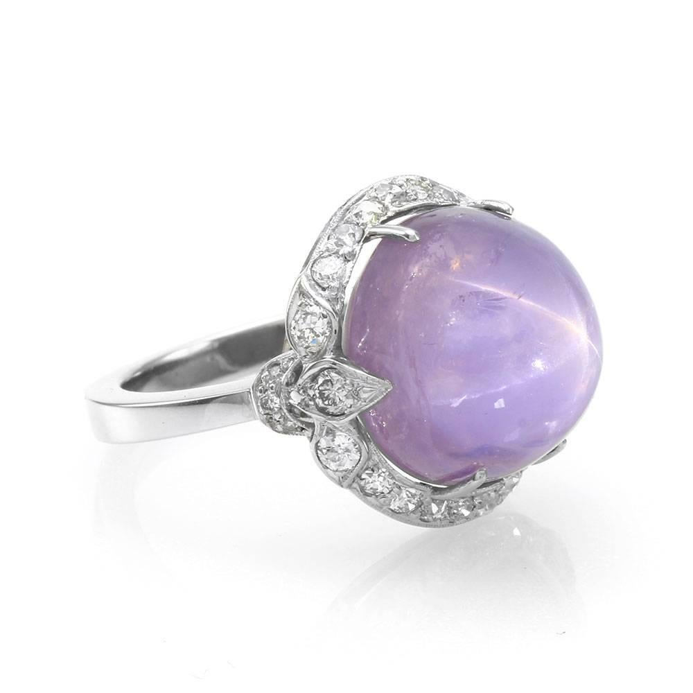 Antique Edwardian star sapphire and pavé diamond halo ring in platinum. There are one round high dome lavender star sapphire (24.00ct) and twenty-eight European and transitional cut diamonds total (0.62ctw) with a color of G-I and a clarity of SI.