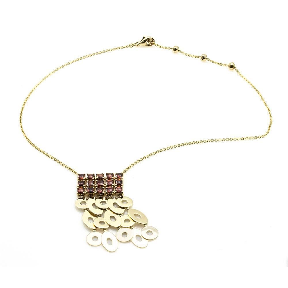 Signed designer Bvlgari (Bulgari) garnet cluster dangle necklace set in 18K yellow gold. There are fifteen square shaped french cut pavilion garnets with buff tops (6.00ctw). The garnet are v-prong set, with open gold discs dangling below the garnet