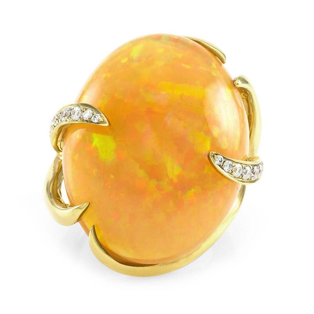 Fire opal and pavé diamond cocktail ring set in 18K yellow gold. There are one oval cabochon opal (26.80ct) and twenty-four round brilliant cut diamonds (0.32ctw) with a color of G-H and a clarity of VS. The opal is fancy prong set, and the