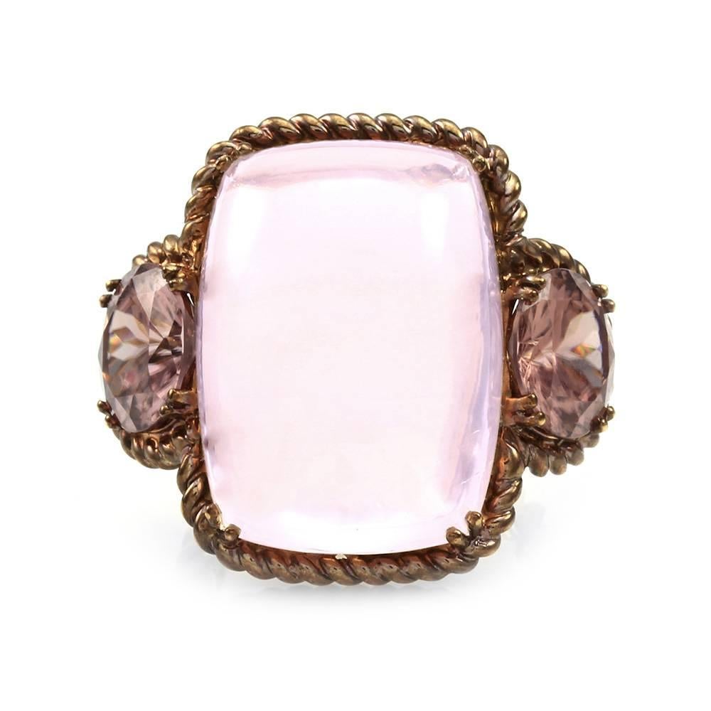 Rose quartz cabochon and fancy cut pink zircon ring in 18K rose finished gold. There are one cushion quartz cabochon (30.99ct) and two round brilliant crown with Portuguese cut pavilion zircons (7.82ctw). The gemstones are double prong set. The ring