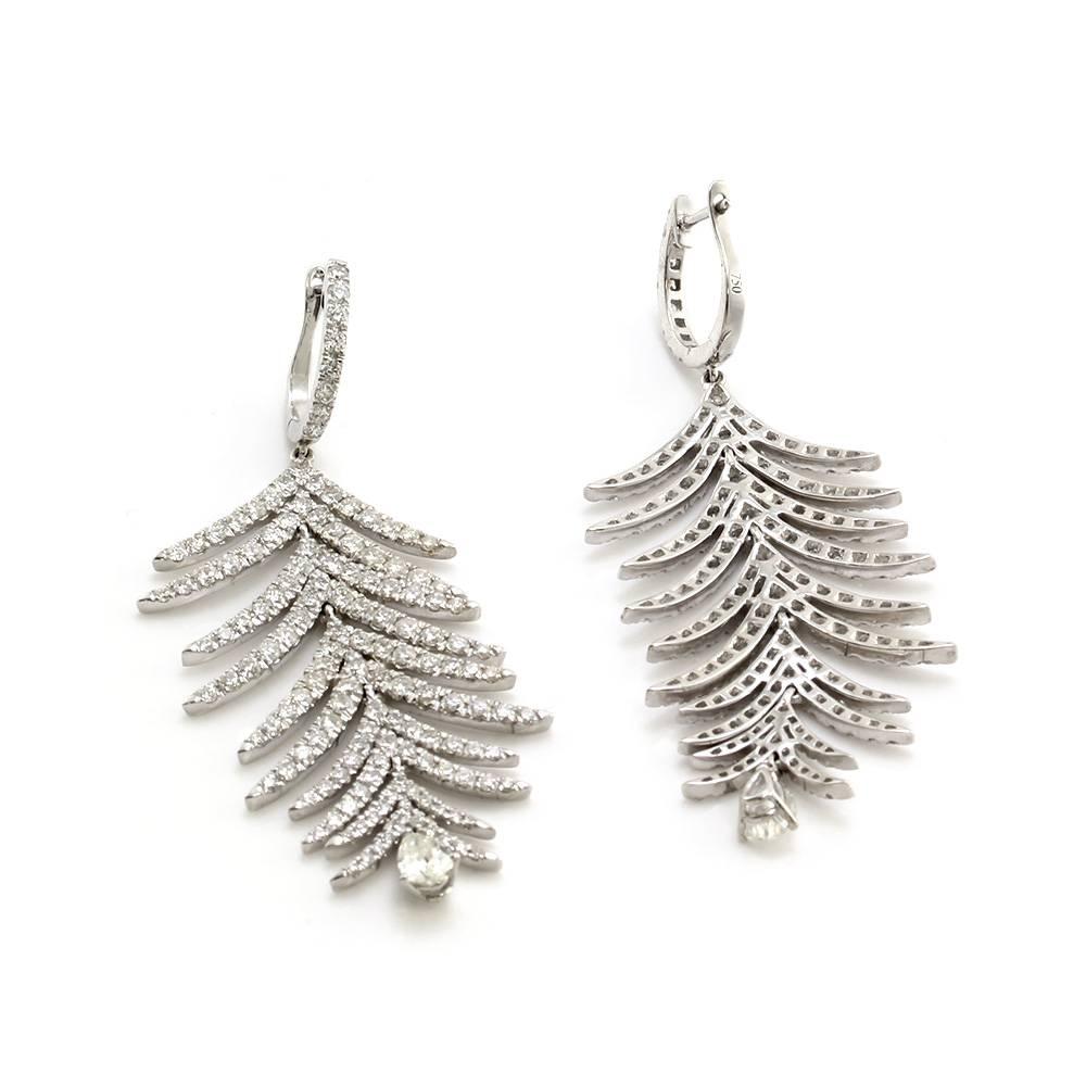 Pavé diamond feather dangle earrings set in 18K white gold. There are two hundred ninety-two round brilliant diamonds and two pear cut diamonds total (5.86ctw) with a color of H-I and a clarity VS. The diamonds are bead set in high polish gold.
