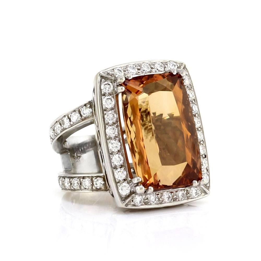 Precious topaz and pavé diamond halo elongated ring set in 18K white gold. There are one rectangular cushion cut topaz (20.53ct) and fifty-eight round brilliant cut diamonds (1.90ctw) with a color of G-H and a clarity of VS. The topaz is prong set,