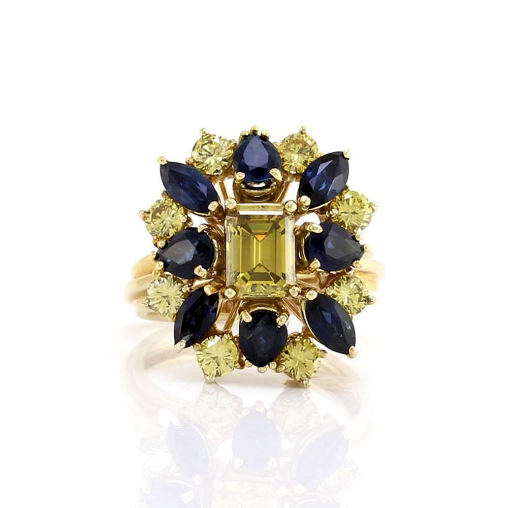 Yellow diamond and blue sapphire cluster ring in 18K yellow gold. There are one emerald cut yellow diamond (1.37ct), eight round brilliant cut yellow diamonds (1.52ctw) and eight pear cut sapphires (3.92ctw). The yellow diamonds have been heat