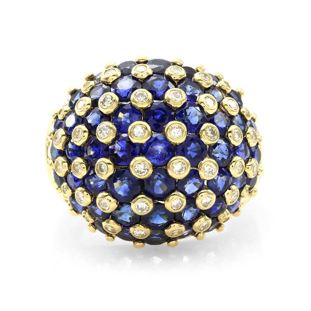 Blue sapphire and diamond dome ring with pavé diamond accents in 18K yellow gold. There are fifty-one round brilliant cut sapphires (7.95ctw) and fifty-eight round brilliant cut diamonds (0.93ctw) with a color of H-I and a clarity of VS-SI. The
