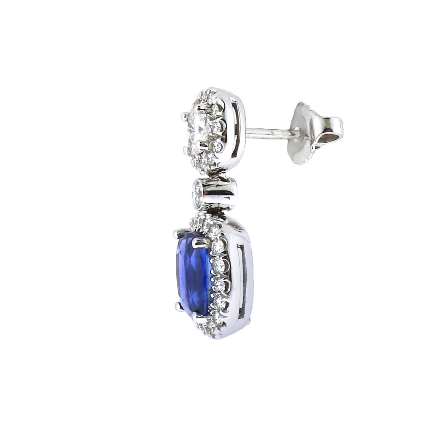 A pair of brilliantly blue, cushion cut sapphires are the centerpiece of these magnificent earrings. The sapphires gracefully drop from two cushion cut diamonds surrounded by a halo of round brilliant cut diamonds.
•Pair of sapphires total 3.43