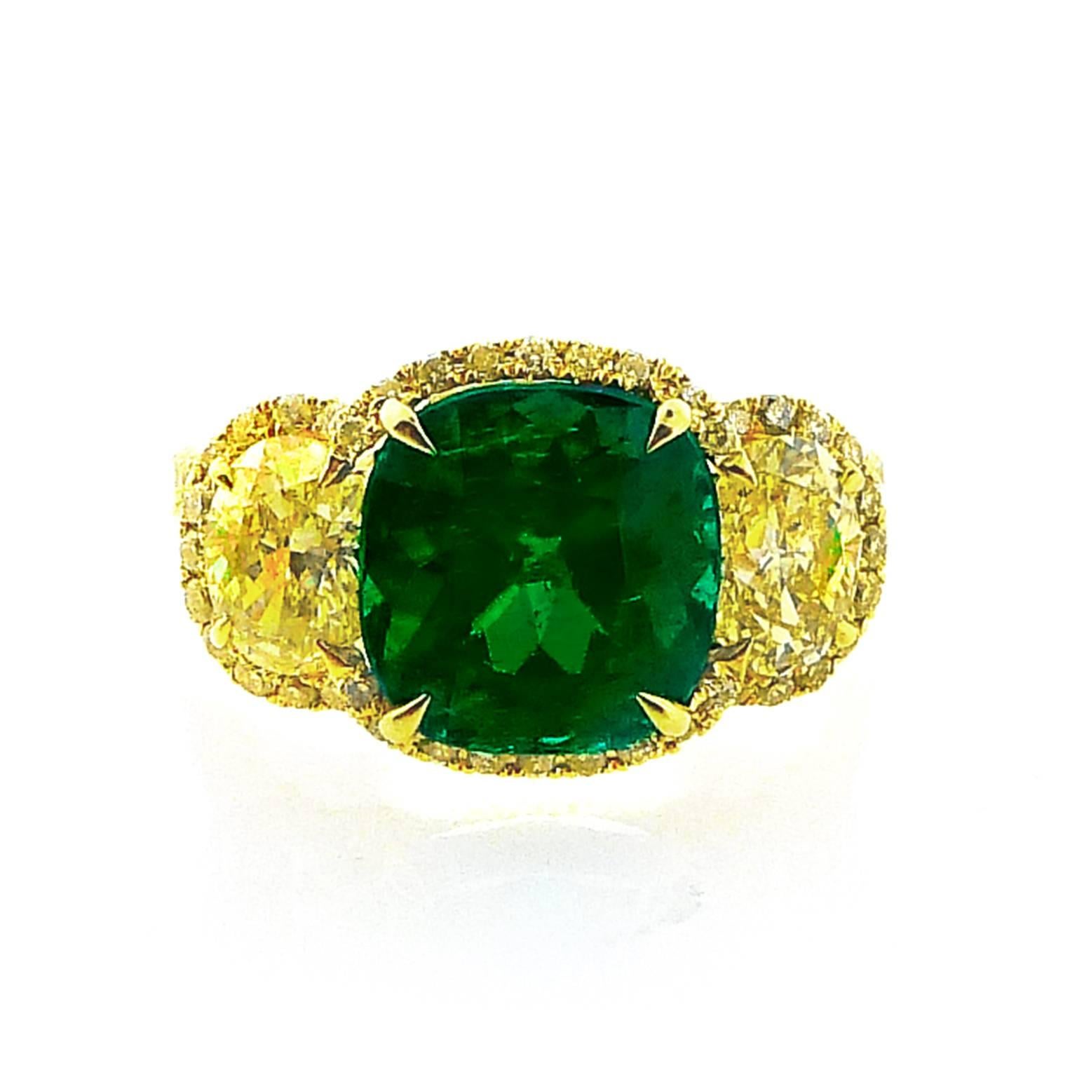 GRS Swisslab certified natural Colombian emerald weighing 2.85 carats with minor oil is set in 18 karat yellow gold flanked by two GIA certified natural fancy intense yellow oval diamonds weighing .53 carats each and totaling 1.06 carats.  In