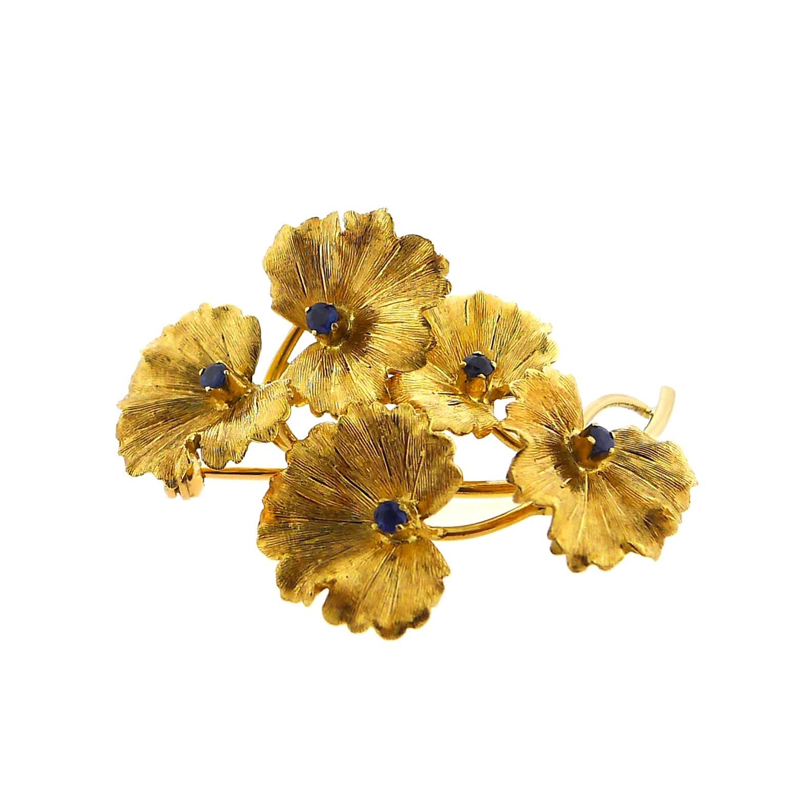 18 karat yellow gold Tiffany flower pin with five small round sapphires measures 2 inches by 1.25 inches and weights 9.5 grams.  