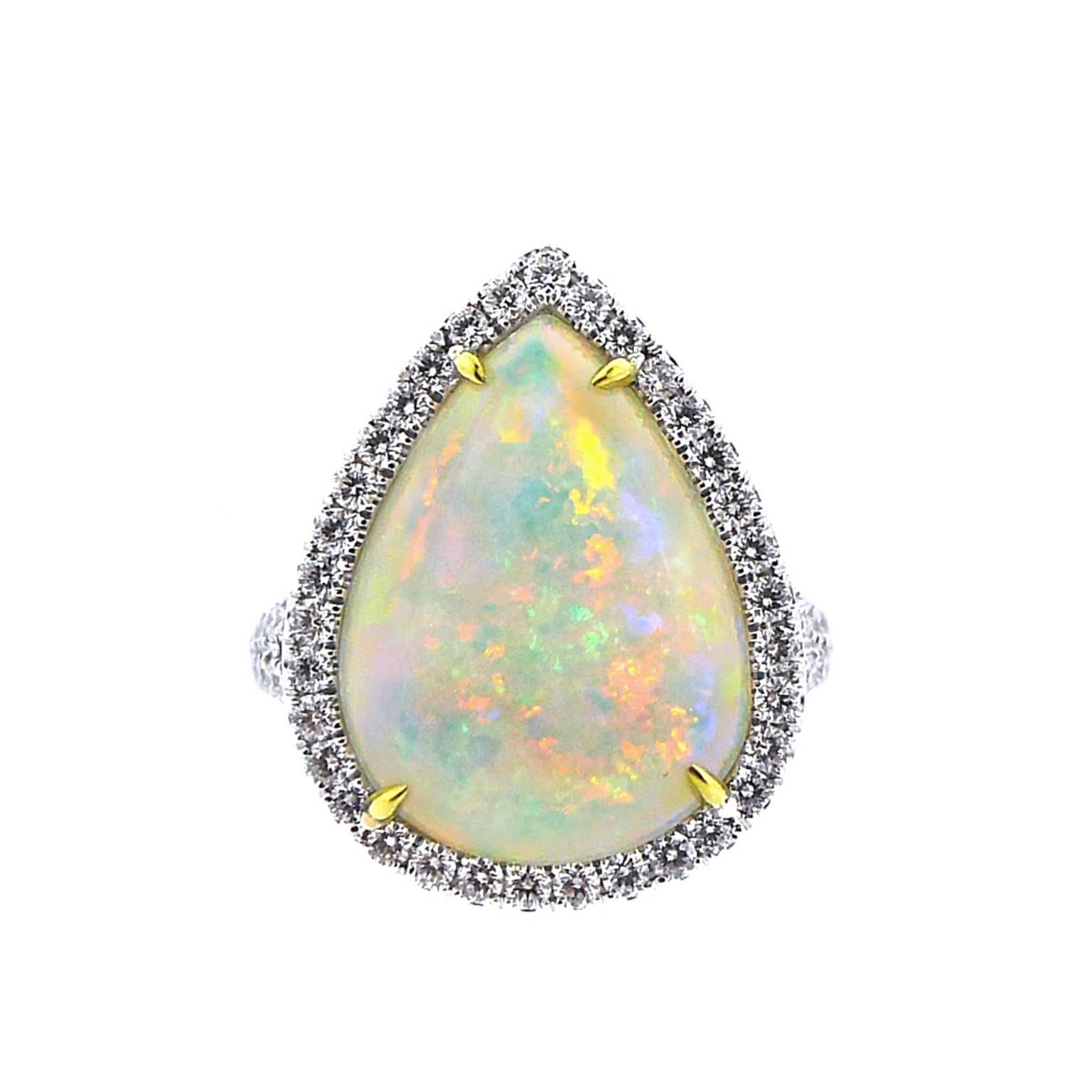Center is a pear shaped opal weighing 4.52 carats and measuring 17 millimeters by 12.13 millimeters. The play of color is moderately strong with predominant reds and oranges and secondary blues and greens. The prongs are handmade 18 karat green