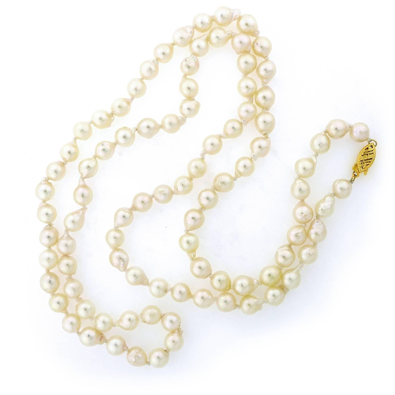 Uniform sized semi-baroque cultured pearls are creamy white colored with hints of pink and peacock. Clasp is 14 karat yellow gold filigree style. Strand measures 30 inches long including the clasp. Pearls have high luster and are overall nice quality