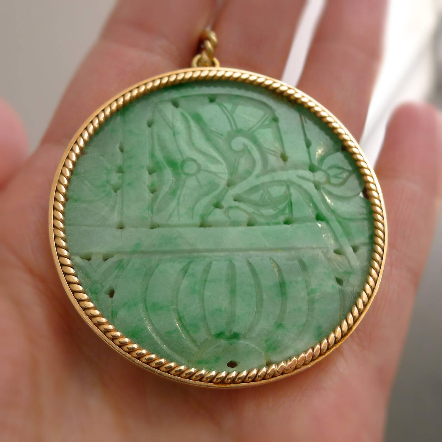 Carved and pierced Jadeite is grayish white with portions of intense apple green. Set in 14K yellow gold twisted wire bezel. 52.5 mm in diameter.
