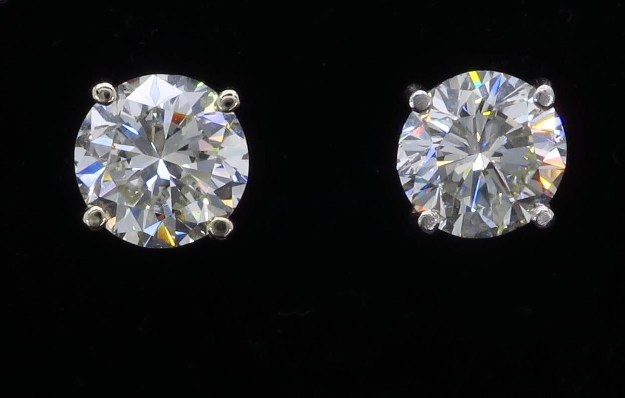 Pair of diamond studs featuring two Round Brilliant Cut Diamonds set in 14k white gold. One diamond is approximately 1.80CT and the other is 1.84CT. The diamonds display J-K color and SI clarity. The total carat weight of the earrings is