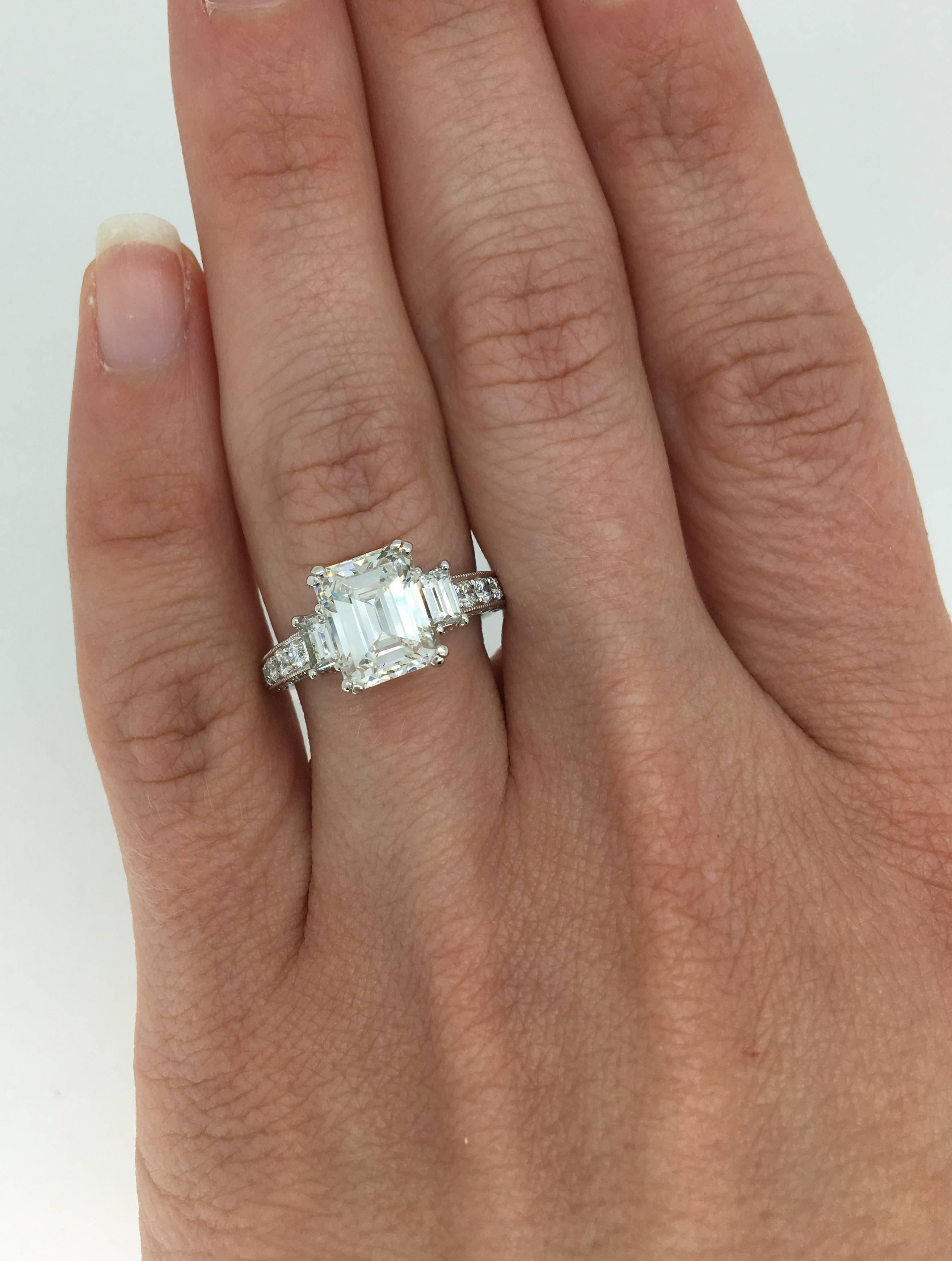 Stunning diamond engagement ring features a large 2.65CT EGL Certified Emerald Cut Diamond in the center with H color, VS1 per EGL. Graded to GIA standards the diamond displays I-J color and VS1-VS2 clarity. There are two additional Emerald Cut