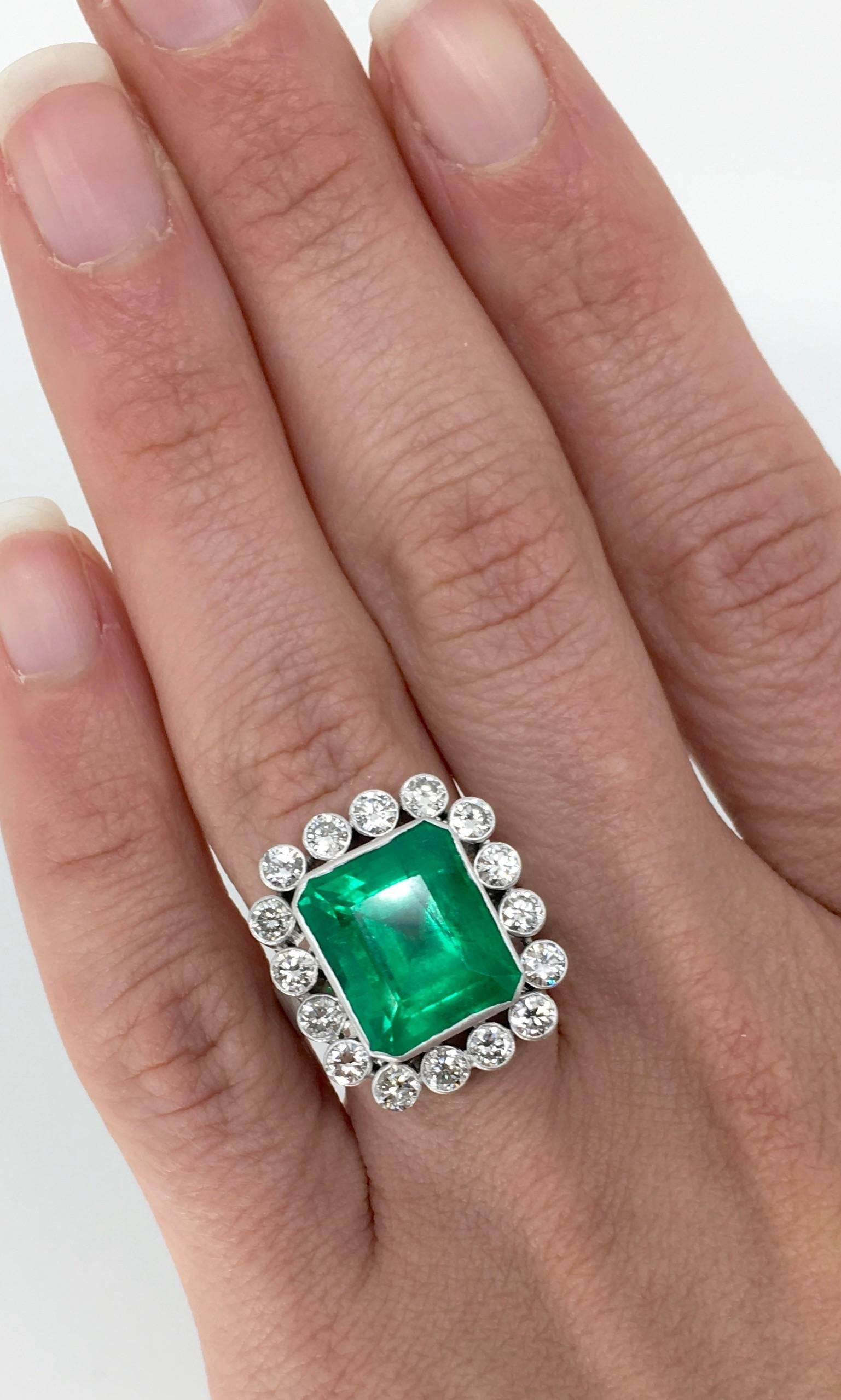 Custom made ring features an Columbian Octagonal Step Cut Emerald, 12.60 X 10.90 X 8.72 MM in size. There are 16 Round Brilliant Cut Diamonds beautifully set in a halo accenting the featured Emerald. The diamonds display G-J color and I1-I2 clarity.
