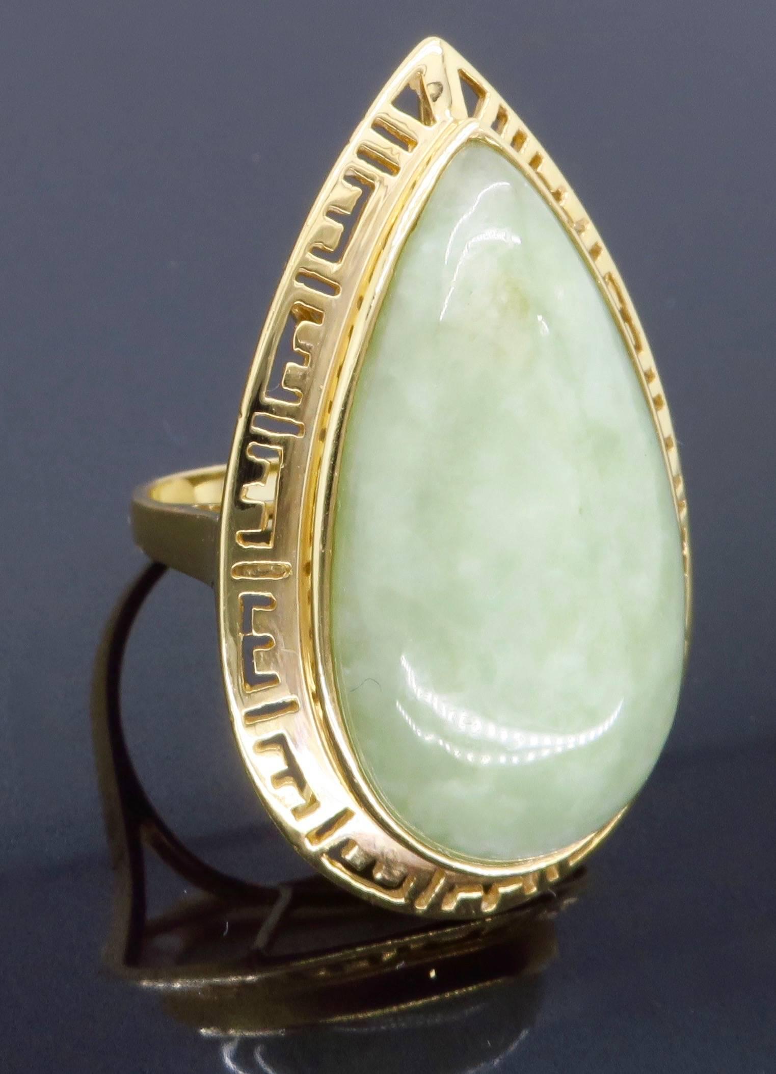 This Sanuk cocktail ring features a 26 x 15 x 6.4 MM Cabochon Cut Jadeite Jade. The featured gemstone is a beautiful semi transparent light mottled green. The 14K yellow gold ring weighs 9.8 grams and is a size 6.