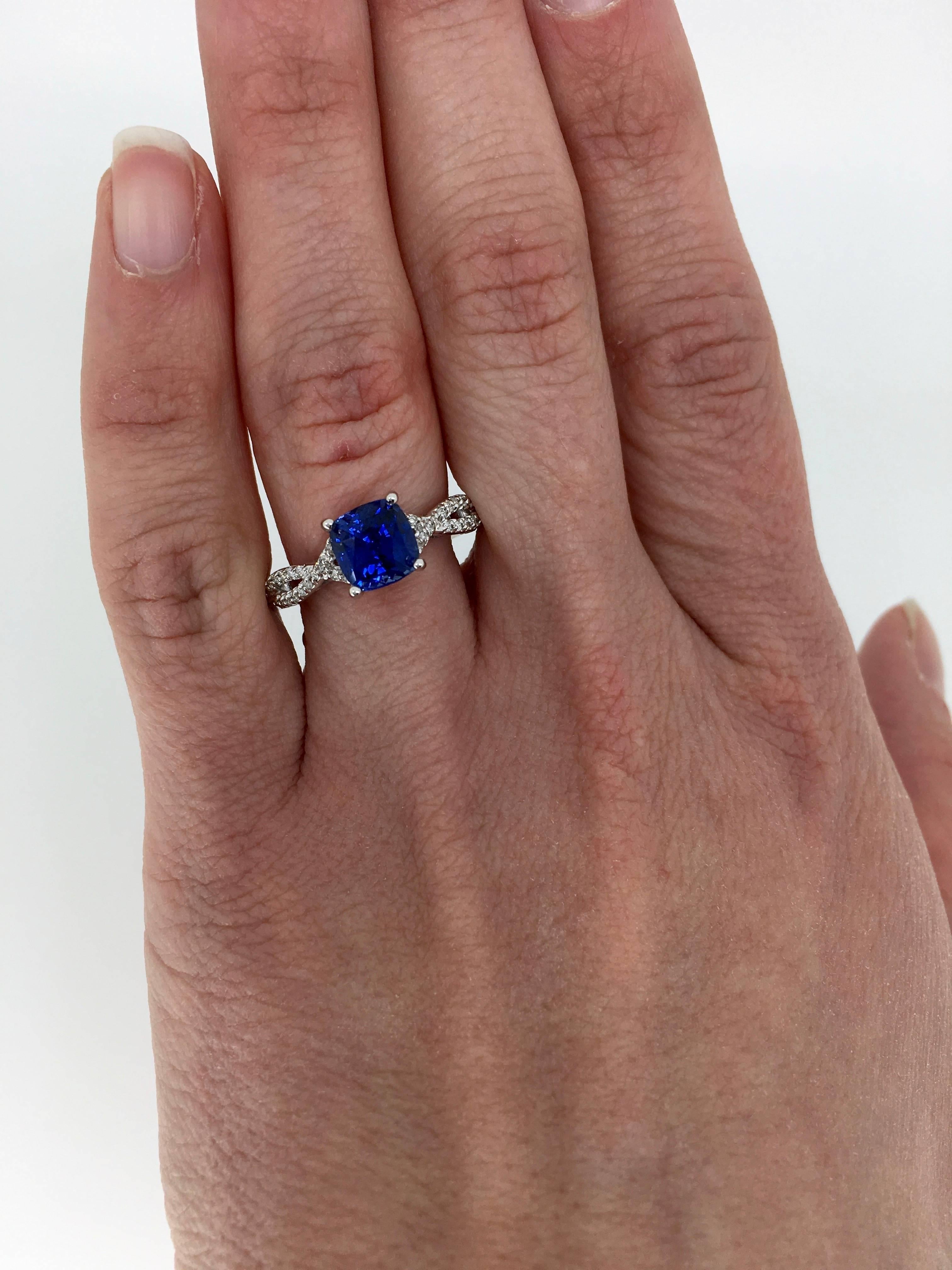 Beautiful engagement ring features a GIA and UGL Certified 2.18CT Cushion Cut Blue Sapphire. The color of the Sapphire is a stunning velvety blue color. The elegant twisted shank of the ring has approximately .35CTW of Round Brilliant Cut Diamonds.