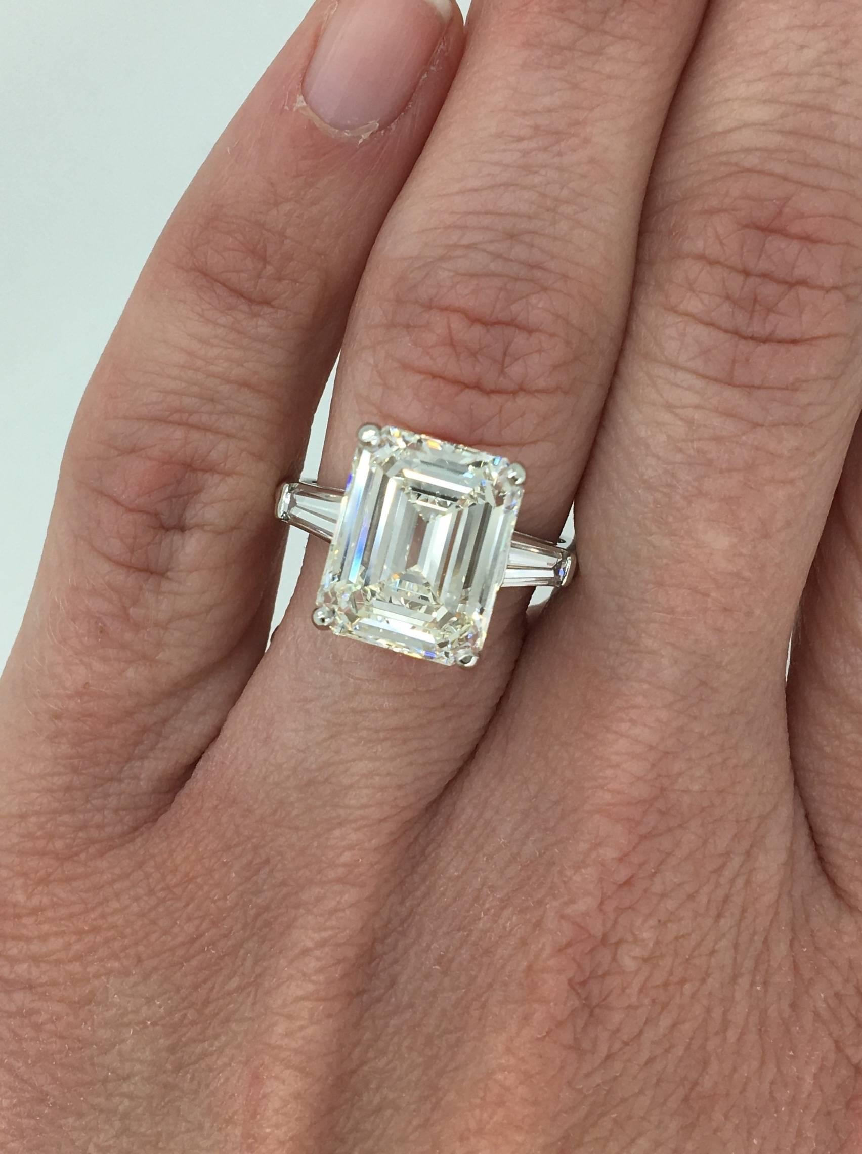 Classic ring features a stunning GIA Certified 6.21CT Emerald Cut Diamond in the center with J color and VS1 clarity. There are two tapered baguettes accenting the featured diamond. The platinum ring houses approximately 6.81CTW of diamonds. This