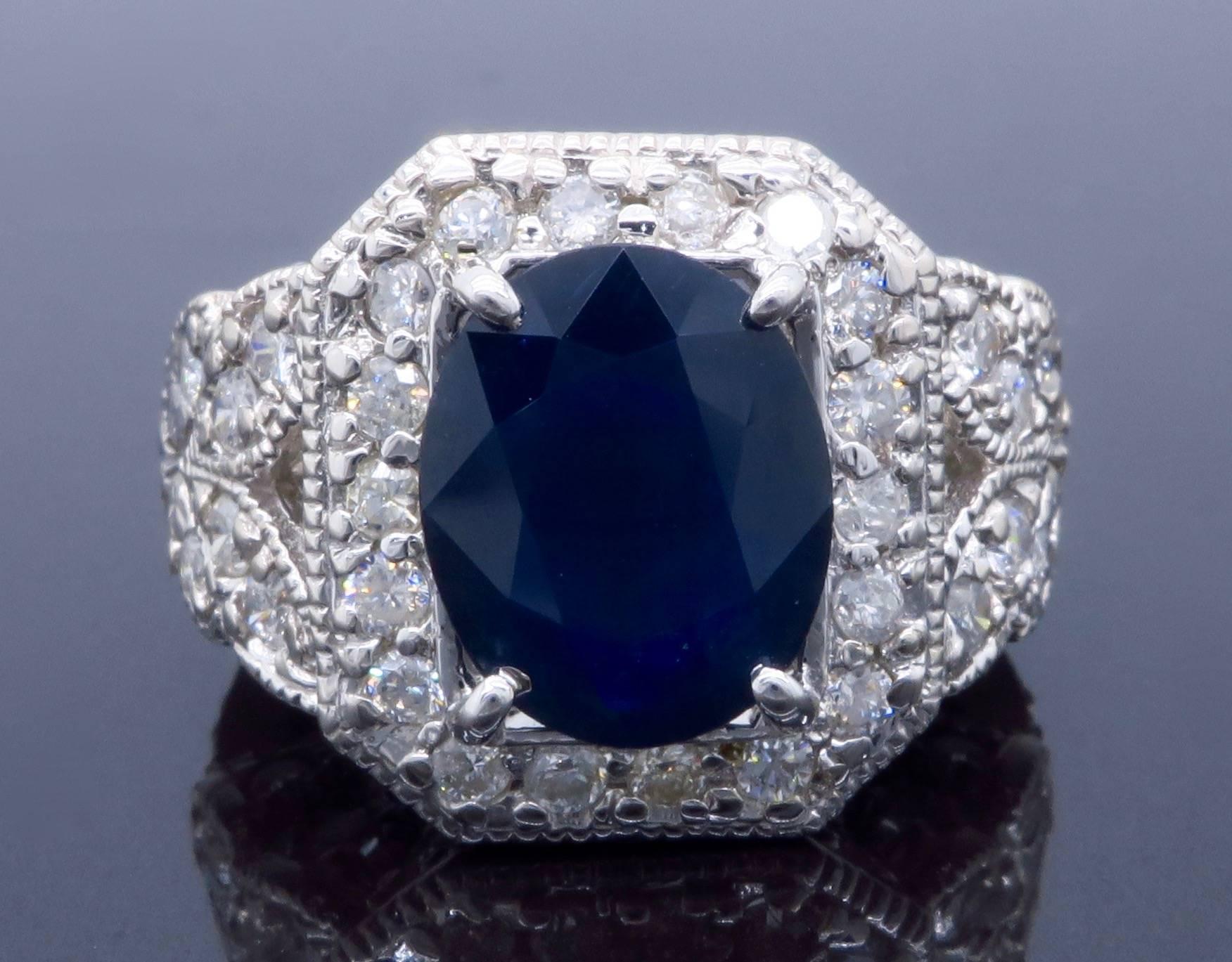 Vintage inspired ring features an approximate 11.80x9.42mm Oval Cut Blue Sapphire. The beautiful 14K white gold ring is adorned with approximately 1.86CTW of Round Brilliant Cut Diamonds. Currently the ring is a size 6.25 and weighs 11.7 grams. The