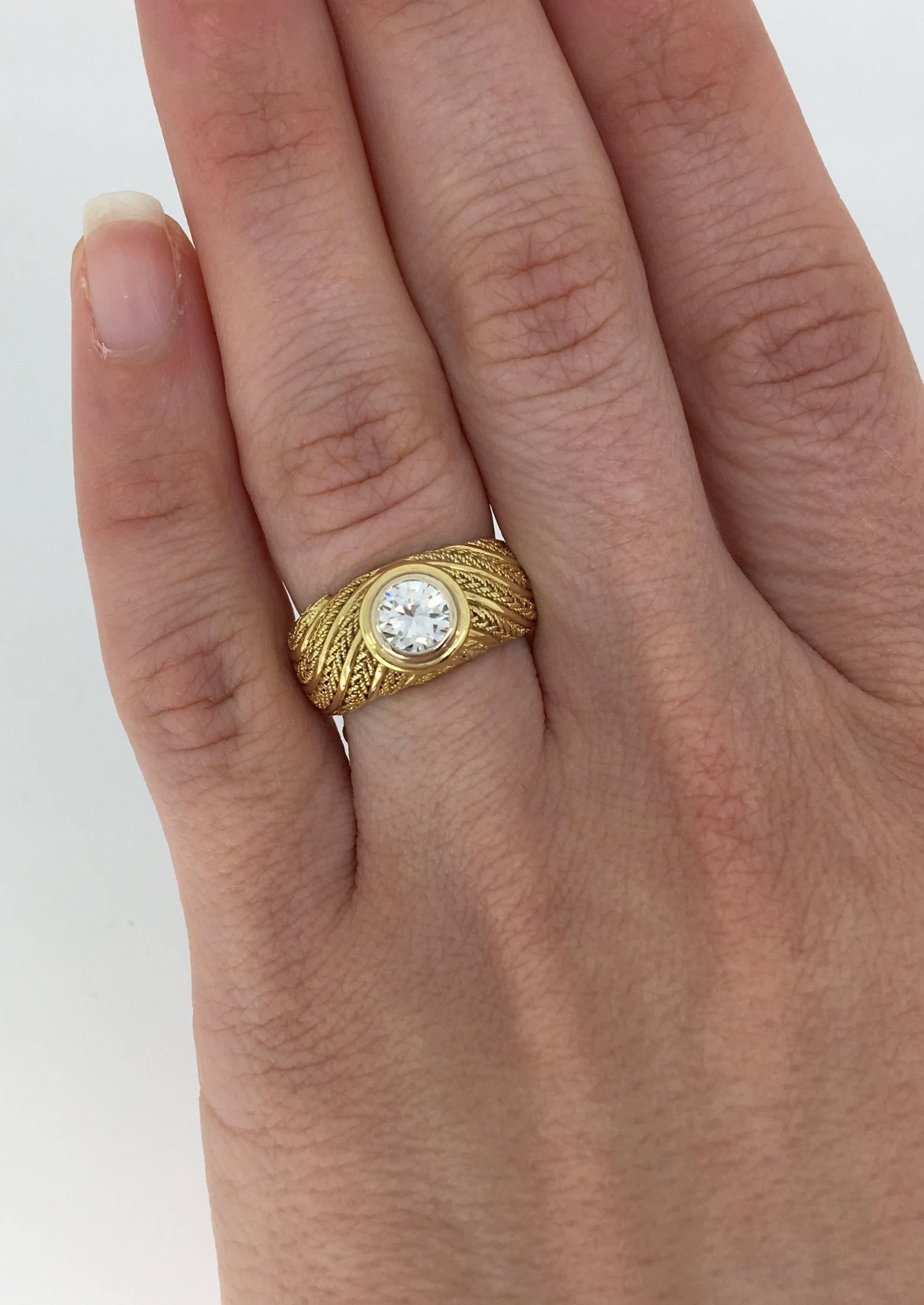 This custom ring features a .78CT Round Brilliant Cut Diamond bezel set in 18k yellow gold. The diamond has I-J color and SI1 clarity. The 18K yellow gold ring was created with a distinctly unique rope-like design. It is currently a size 6.0 and