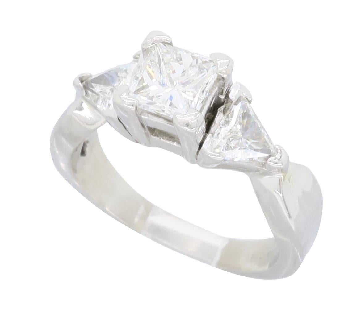Beautiful engagement ring featuring a .70CT Princess Cut Diamond in the center. The diamond has H-I color and VS2 clarity. It is accented by two Trilliant Cut Diamonds. The total diamond weight is approximately 1.24CTW. The platinum ring is size 5.5