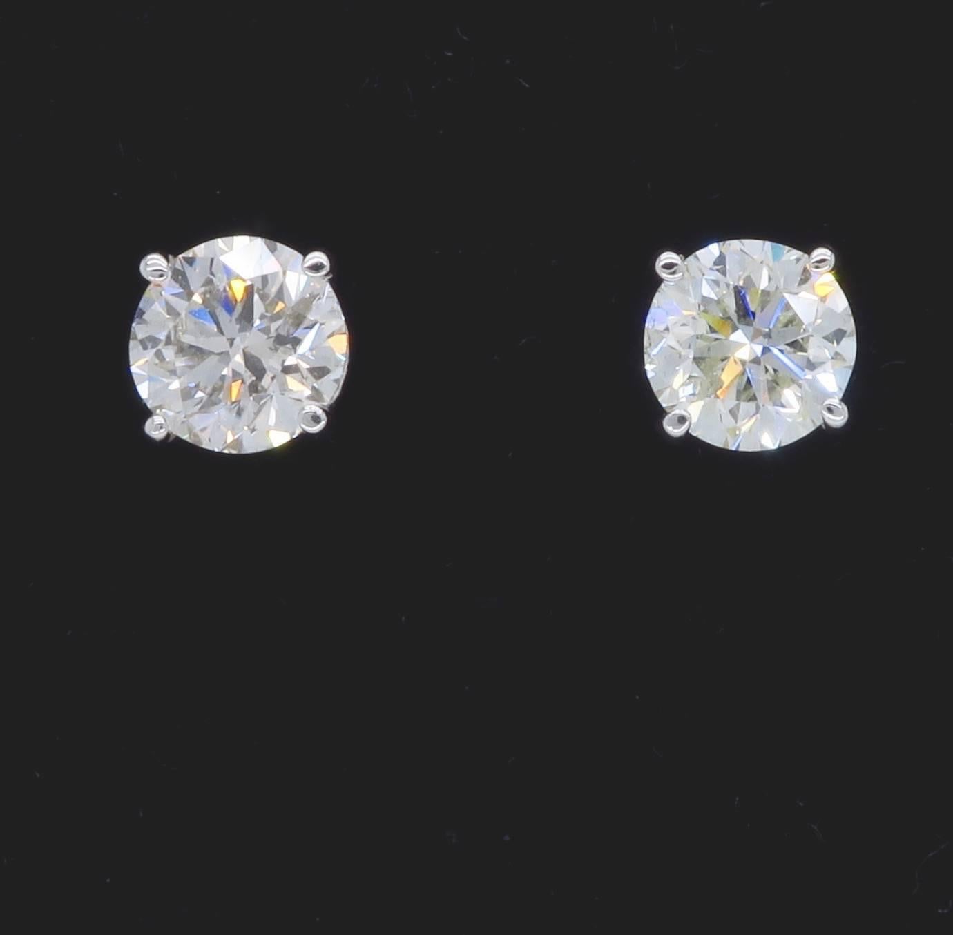 Pair of Round Brilliant Cut Diamond studs is set in a classic 4 prong setting with convenient protector safety backs.  Each earring has an approximately .90CT Round Brilliant Cut Diamond. The diamonds display J-K color and I1 clarity, there are two