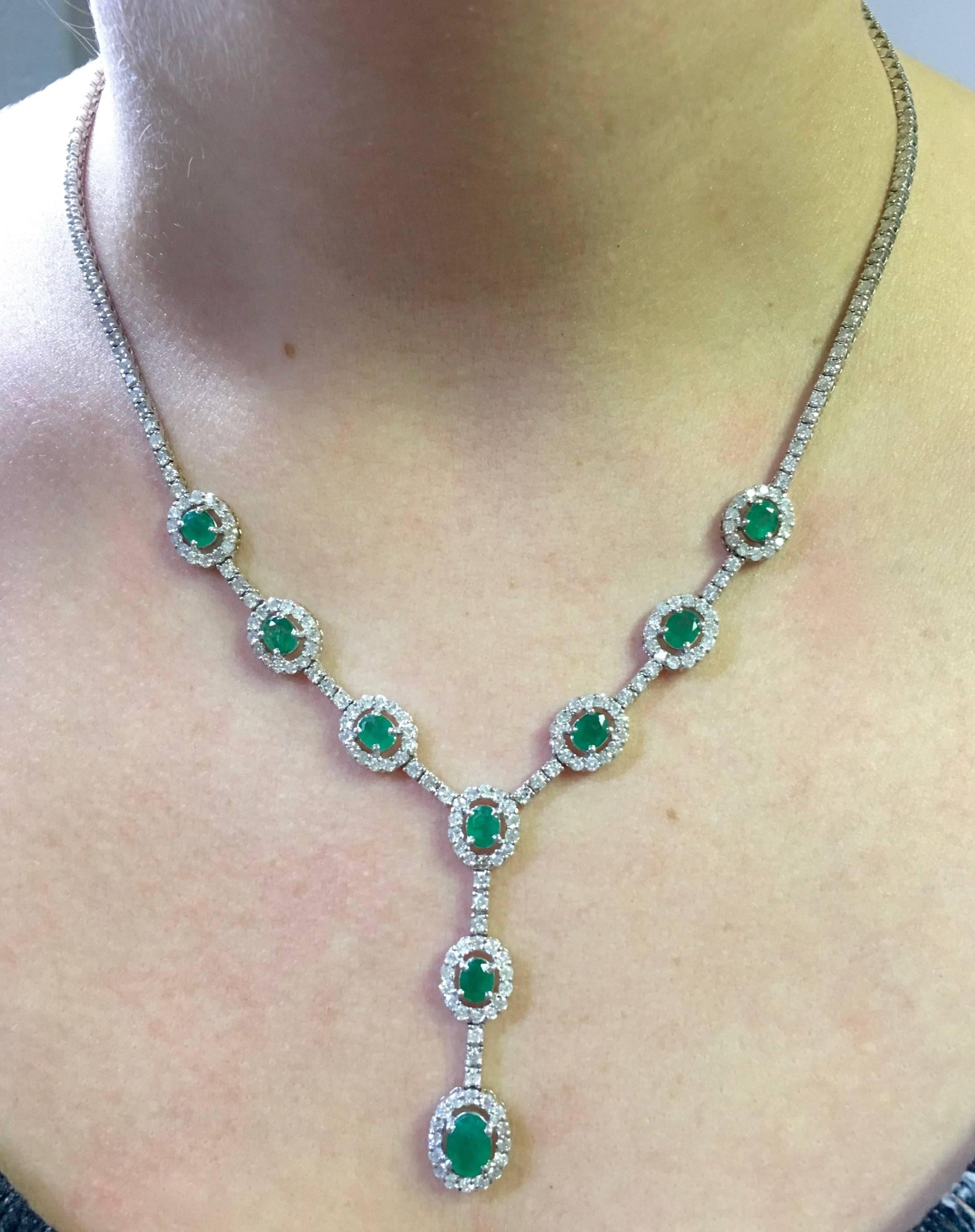 Elegant 14K white gold necklace houses approximately 4.25CTW of Round Brilliant Cut Diamonds, which display an average color of G-J and an average clarity of I1. The Diamonds elegantly surround 9 Oval Cut Emeralds. The center emerald measures