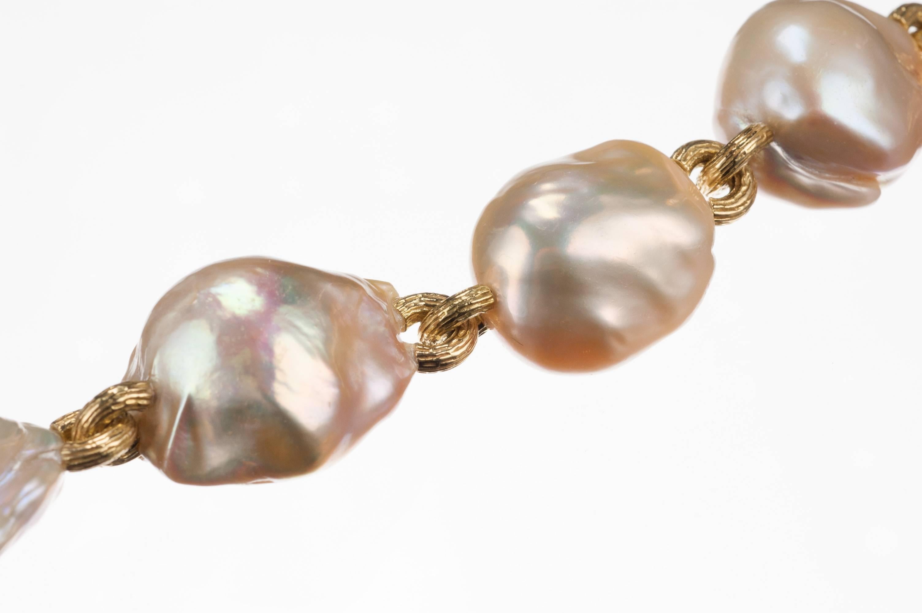 Seven multi-colored freshwater cultured baroque pearls are connected by textured 18-karat yellow gold links. Shades of blush, white, grey, and green create a soft blending of tones. This chunky bracelet, from Israeli designer Yvel, also has a