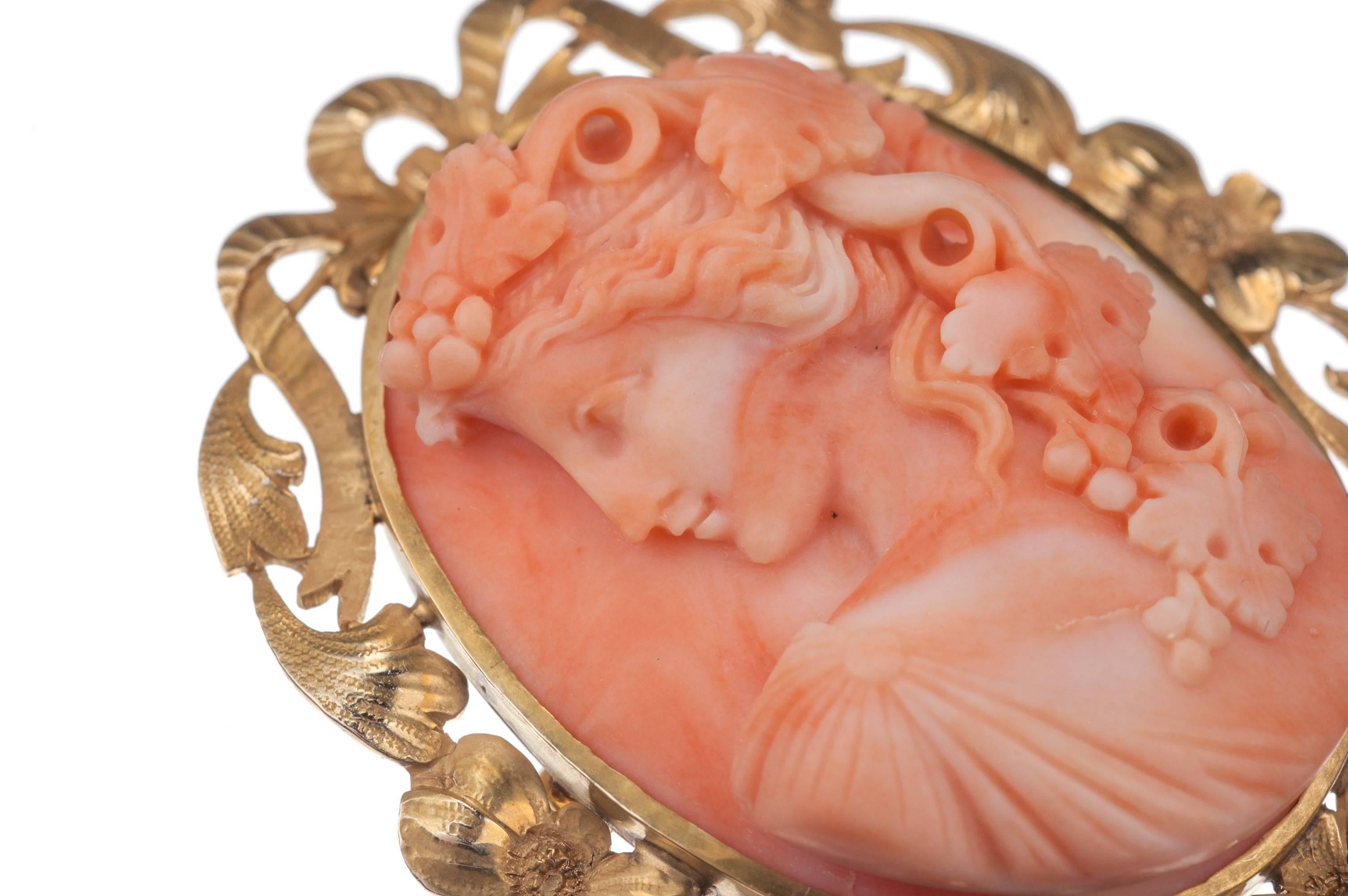Sculpted from creamy pink-orange coral, a cameo brooch in 14-karat yellow gold. Fitted with a swivel bail that discreetly folds away, the brooch can strung along a necklace or simple ribbon to be worn as a pendant. Measures approx. 1.75” long.