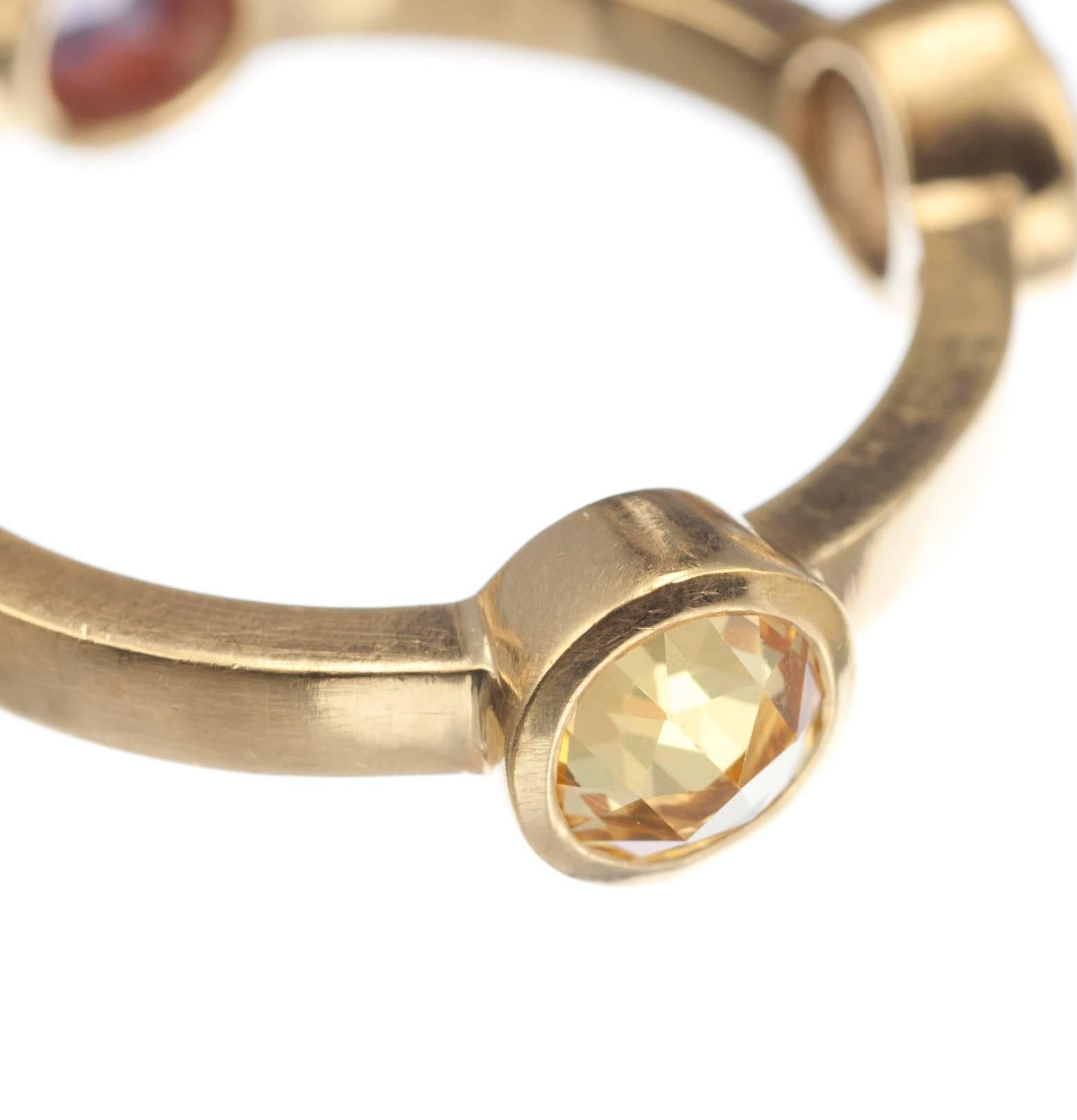 Rose-cut yellow, pink, purple and green sapphires are stationed at regular intervals on a brushed, 22-karat yellow gold band. The bezel-set round gemstones, 4.5mm, glitter in this understated and unique ring. Size 6.