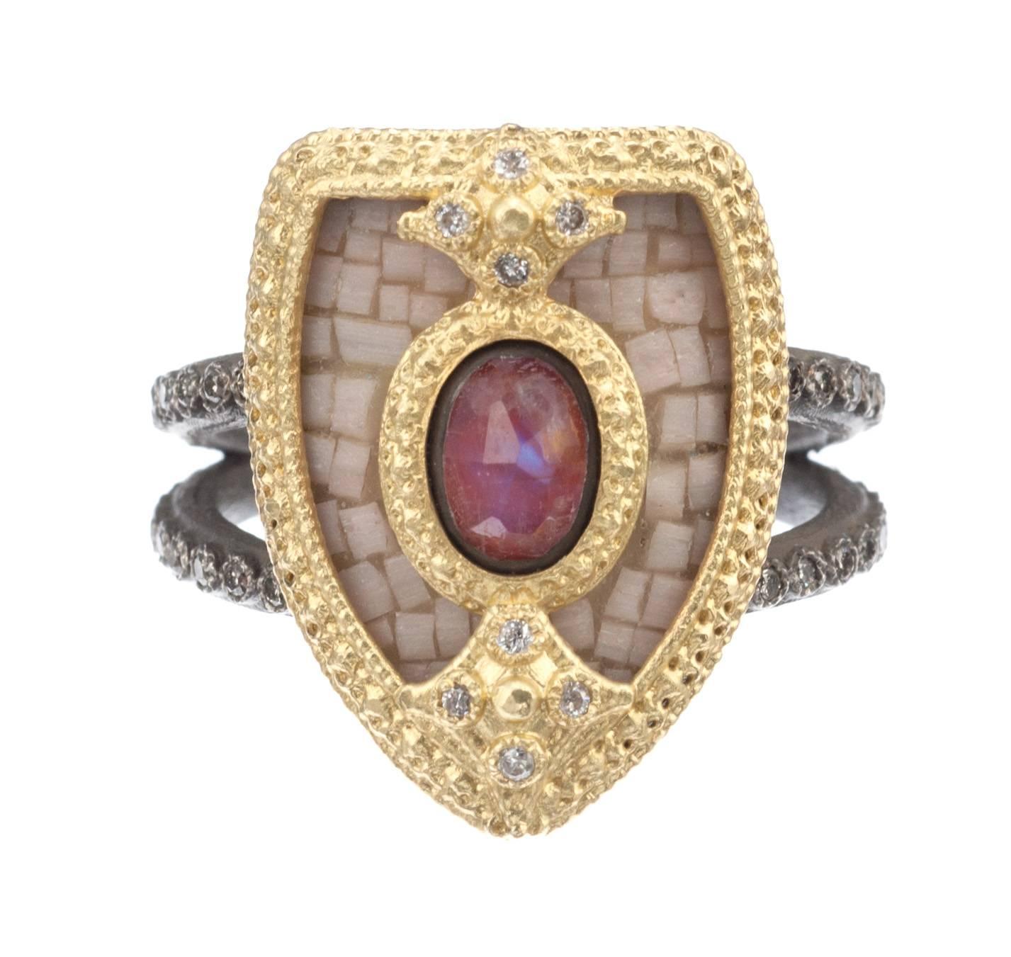 Possessed of a distinctive heraldic charm, a shield ring from Armenta’s ‘Old World’ collection. The shield is covered with a mosaic of soft white glass tiles and emblazoned with a oval doublet of rainbow moonstone and red jasper. Framing the