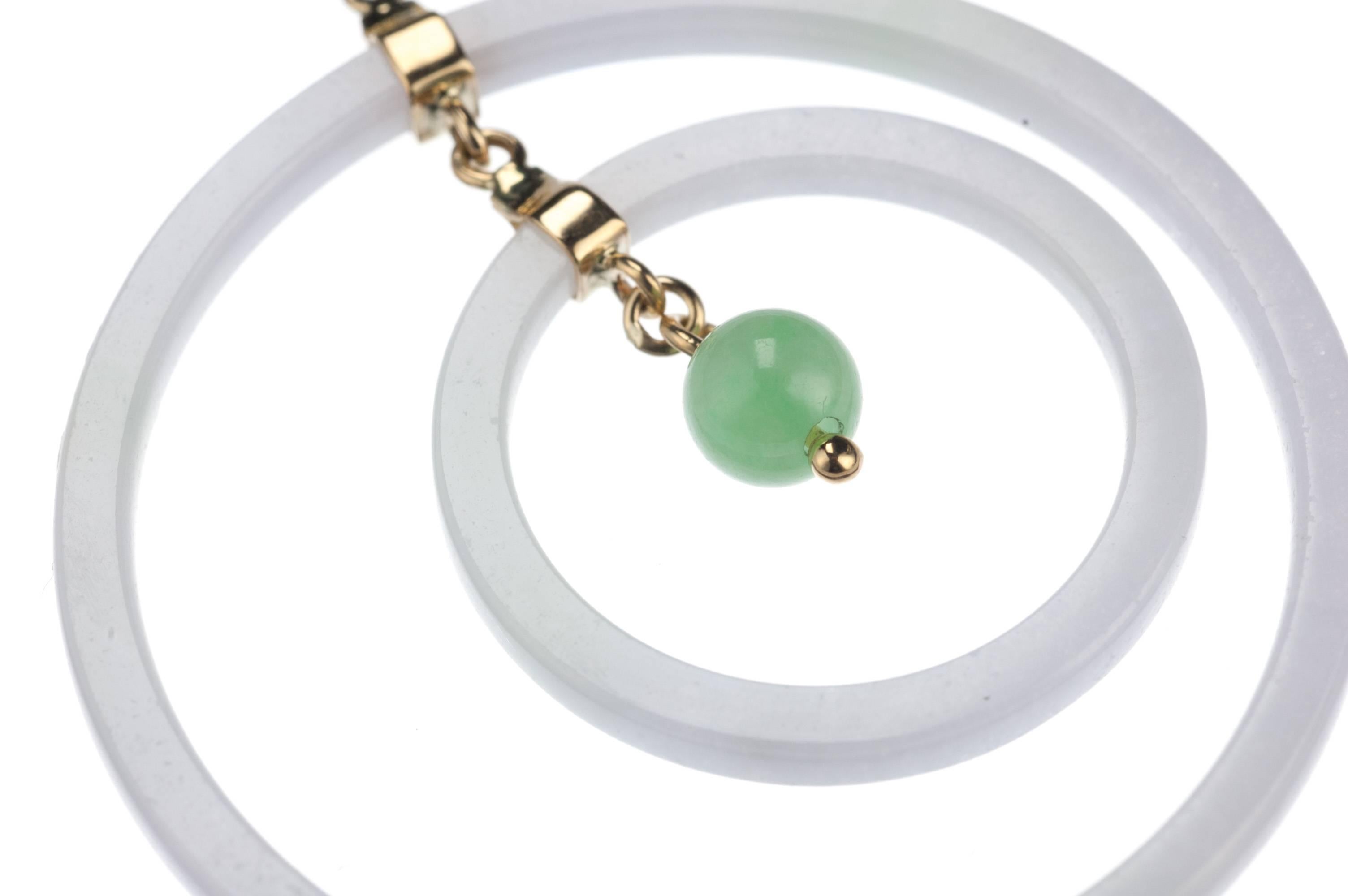 Concentric rings of white jadeite encircle small green jadeite beads suspended from these 18-karat yellow gold drop earrings. Measuring approx. 3” long and 1.5” wide, these earrings make a bold statement without sacrificing their delicate, feminine