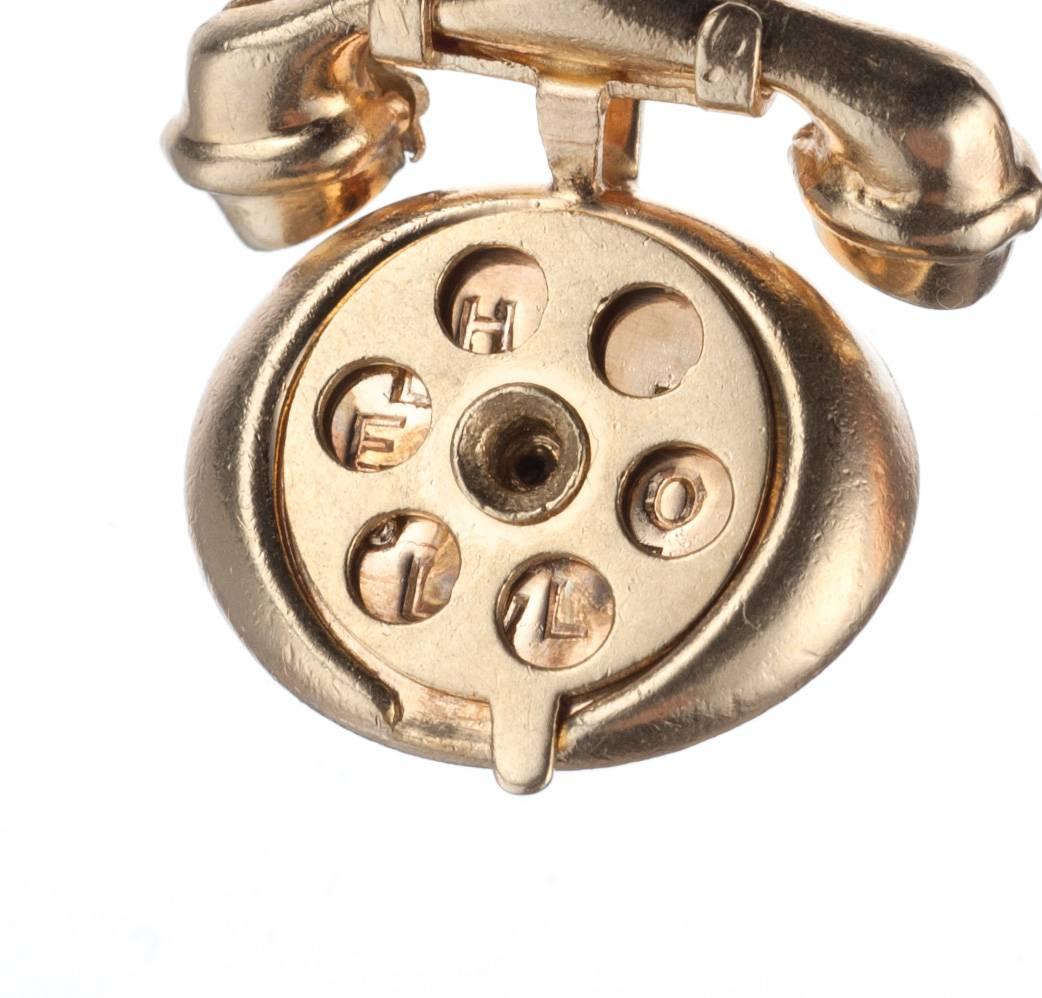 A rotary telephone charm made in 14-karat yellow gold. The phone’s rotating mechanism is cleverly designed to reveal two different messages when shifted: “I LOVE U” and “HELLO.” The bottom of the charm includes an engraved date from the previous