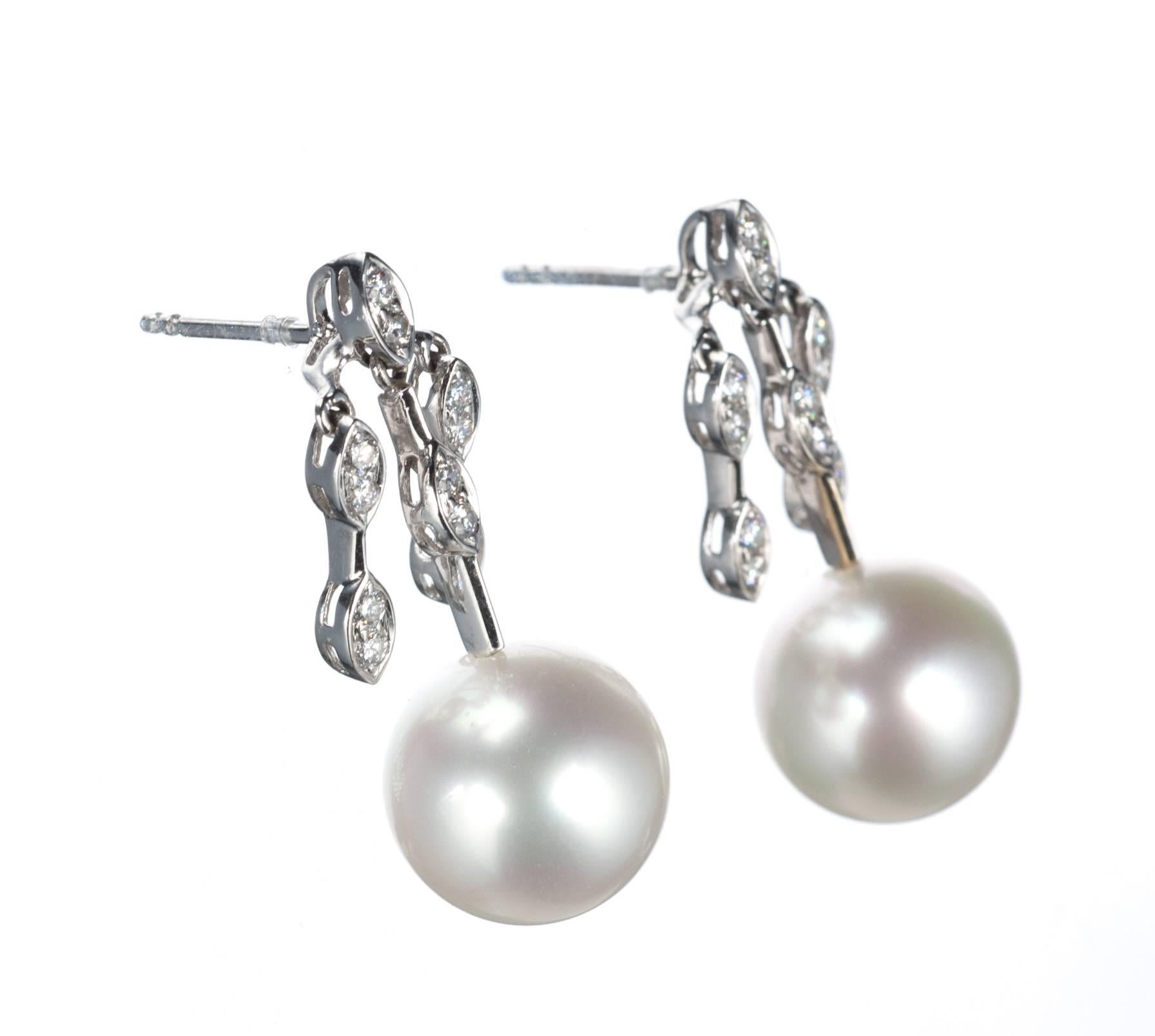 Gently glinting on the ear, a pair of south sea cultured pearl earrings accented with 24 brilliant-cut round diamonds, .43ctw. of G color and VS clarity, set in descending lines of 18-karat white gold. Secured on posts with friction backs. Measure